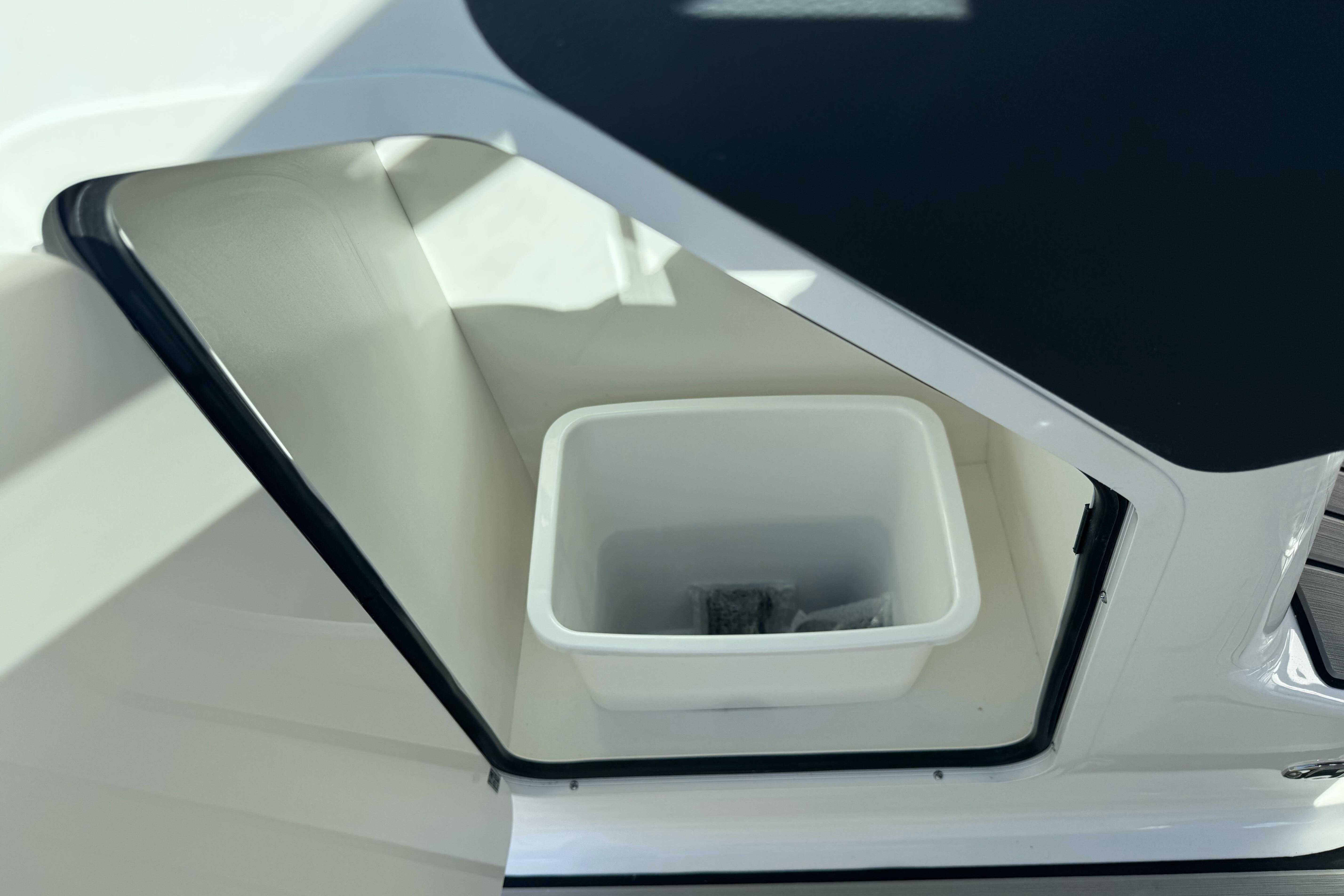 Storage compartment on 2026 Sea Ray SLX 260 boat with white container inside.