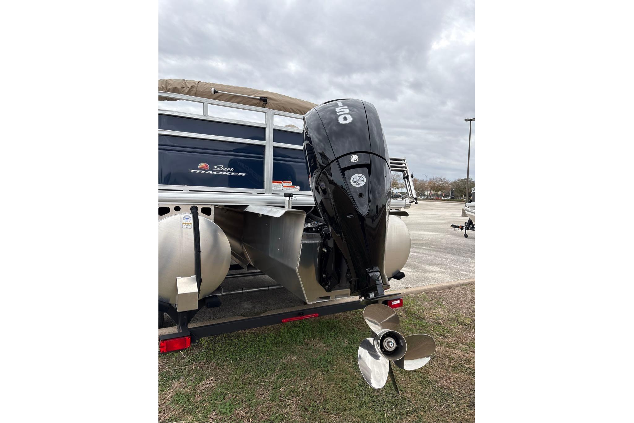 2025 Sun Tracker Fishin' Barge 22 XP3 with powerful outboard motor in parking lot.