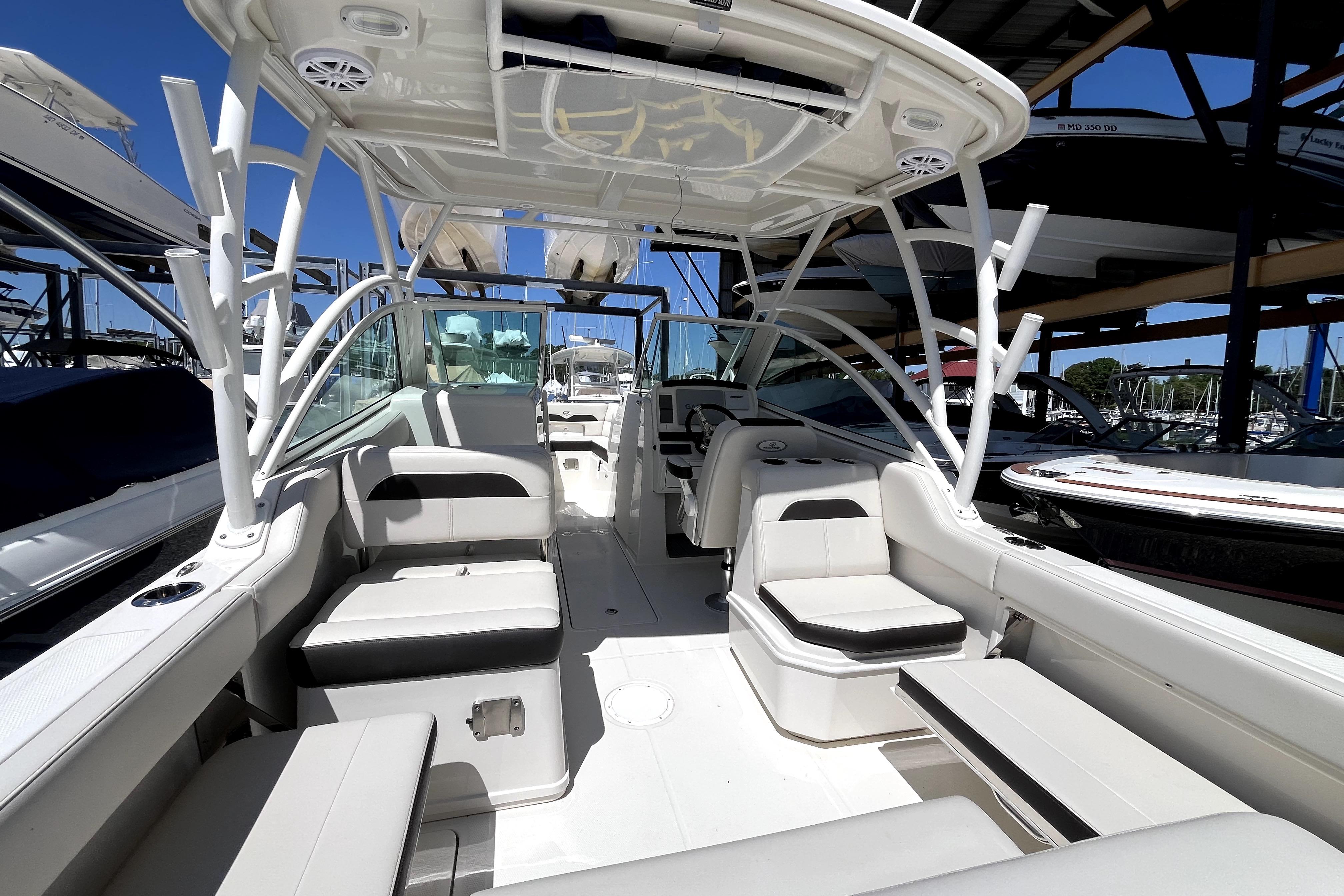 2024 Sailfish 245 DC boat interior with seating and canopy in marina setting.
