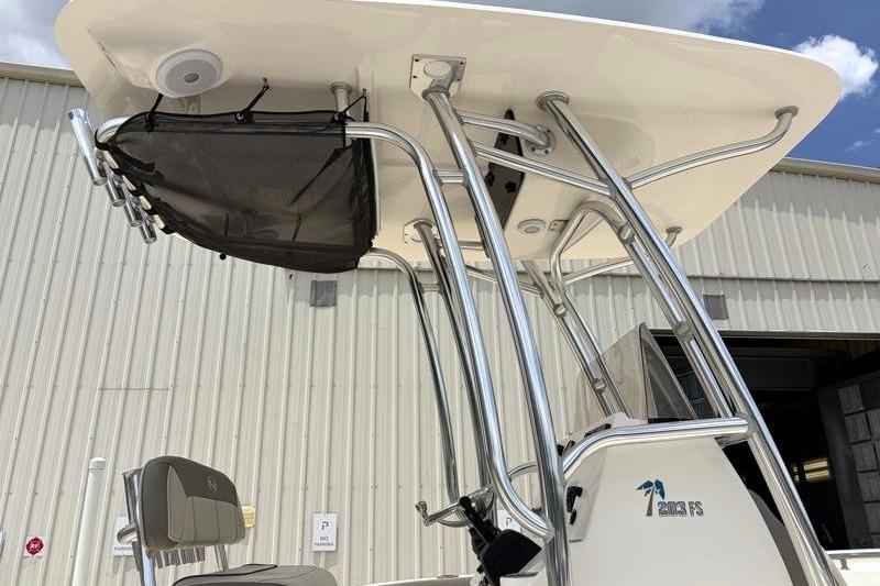 2023 Key West 203 FS boat with T-top and rod holders, parked near a warehouse.