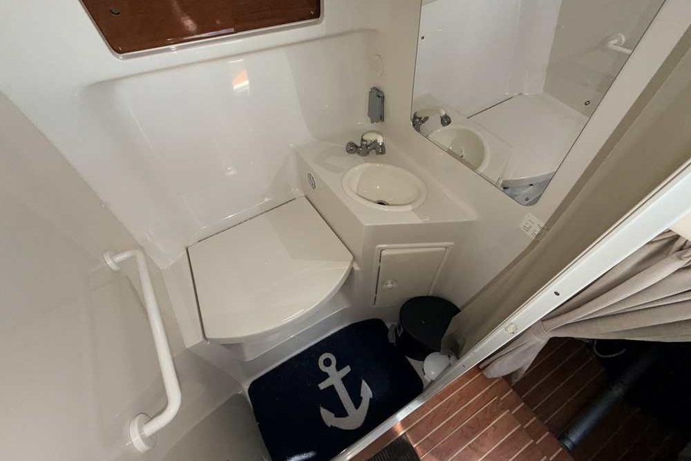 Compact bathroom in 2001 Monterey 282 Cruiser with toilet, sink, and nautical-themed mat.