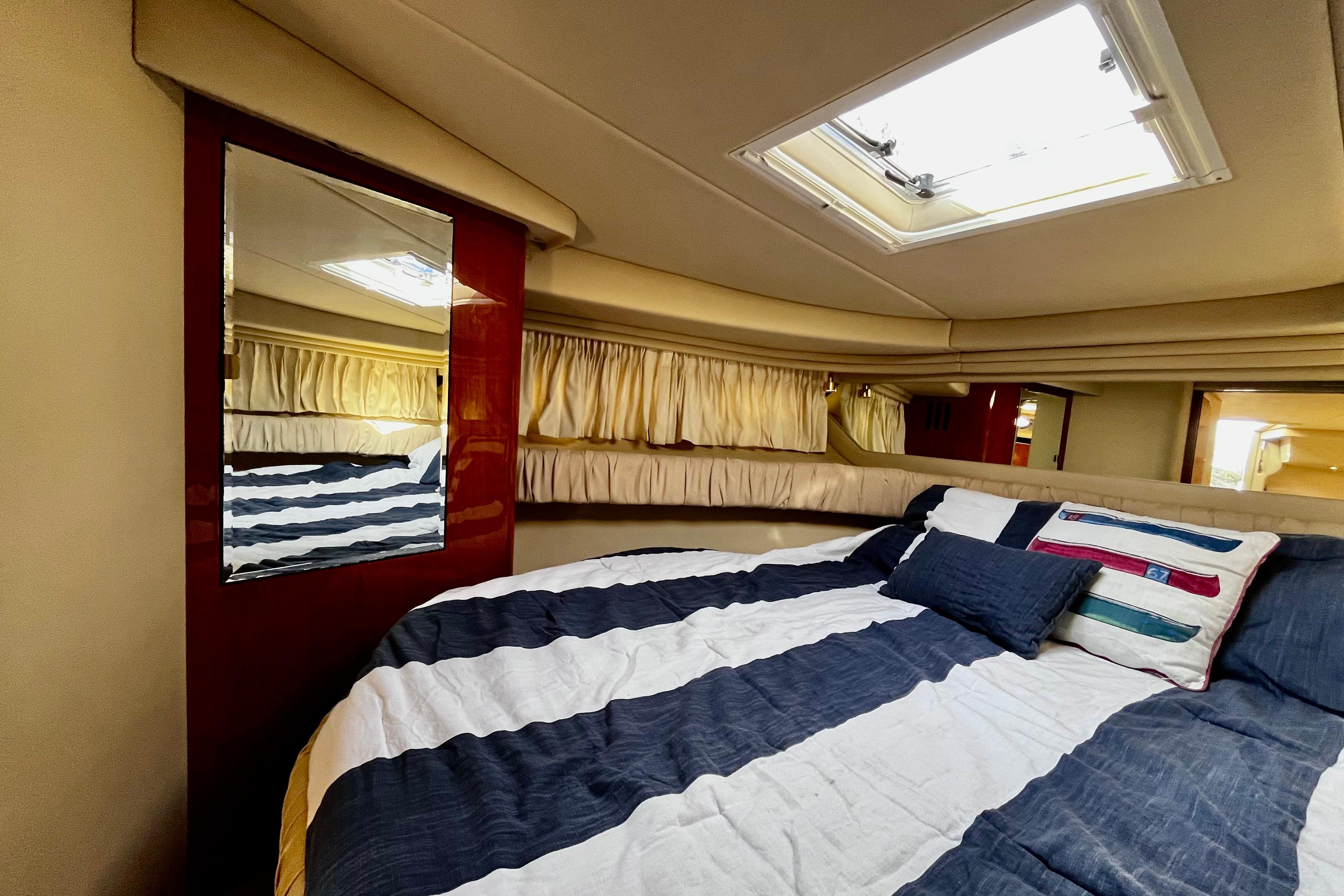 Cozy cabin interior of 2000 Sea Ray 380 Sundancer with striped bedding and skylight.