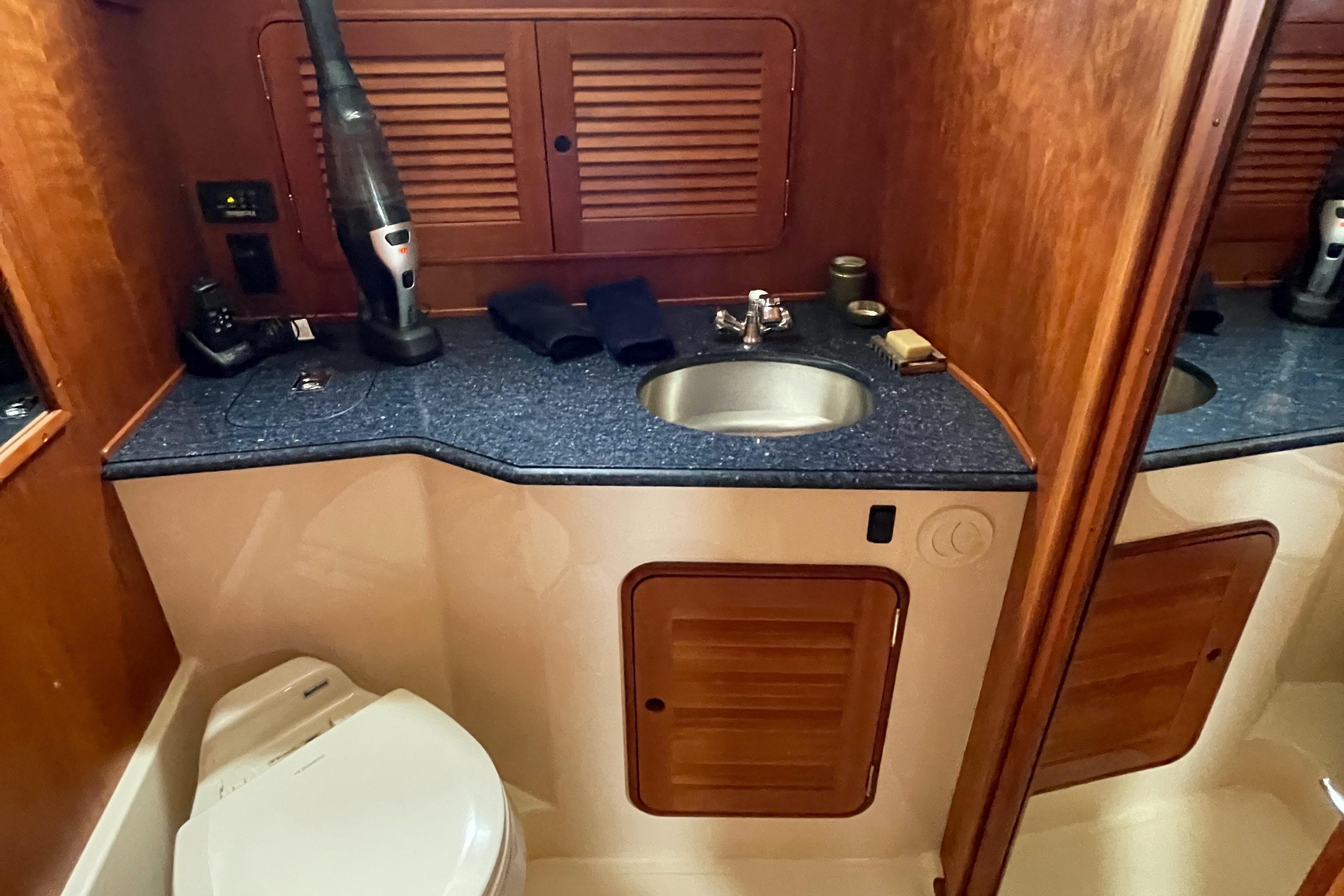 2007 Hinckley Talaria 44 Flybridge bathroom with sink, toilet, and wooden cabinetry.