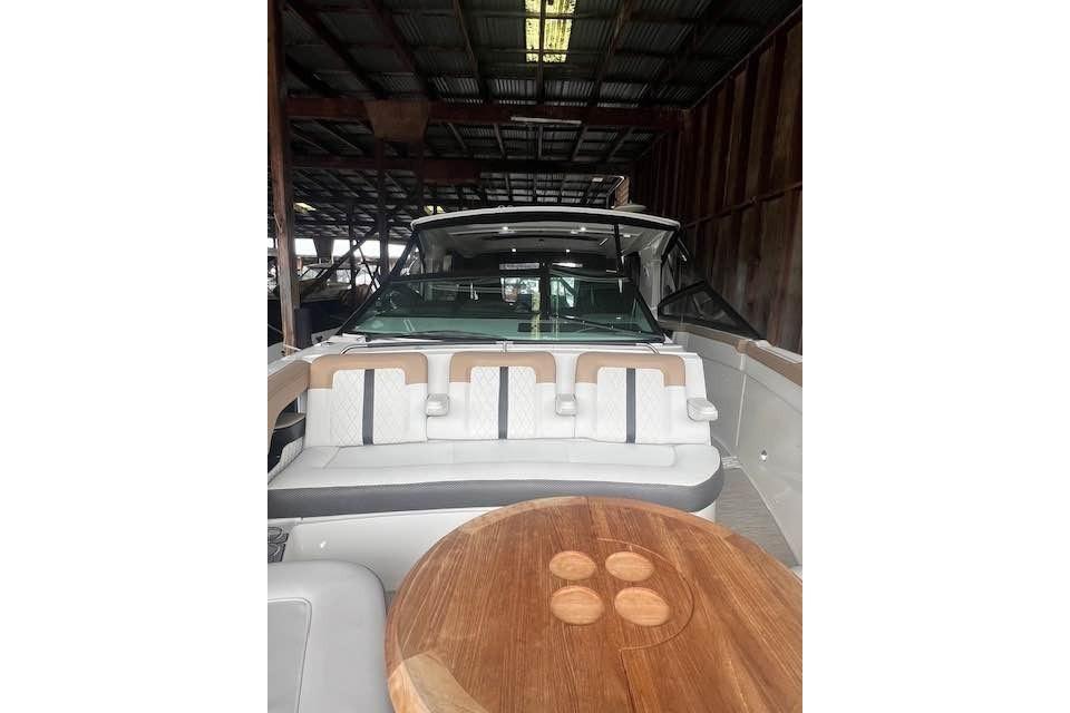2018 Sea Ray SLX 400 boat interior with seating and wooden table in a covered dock.