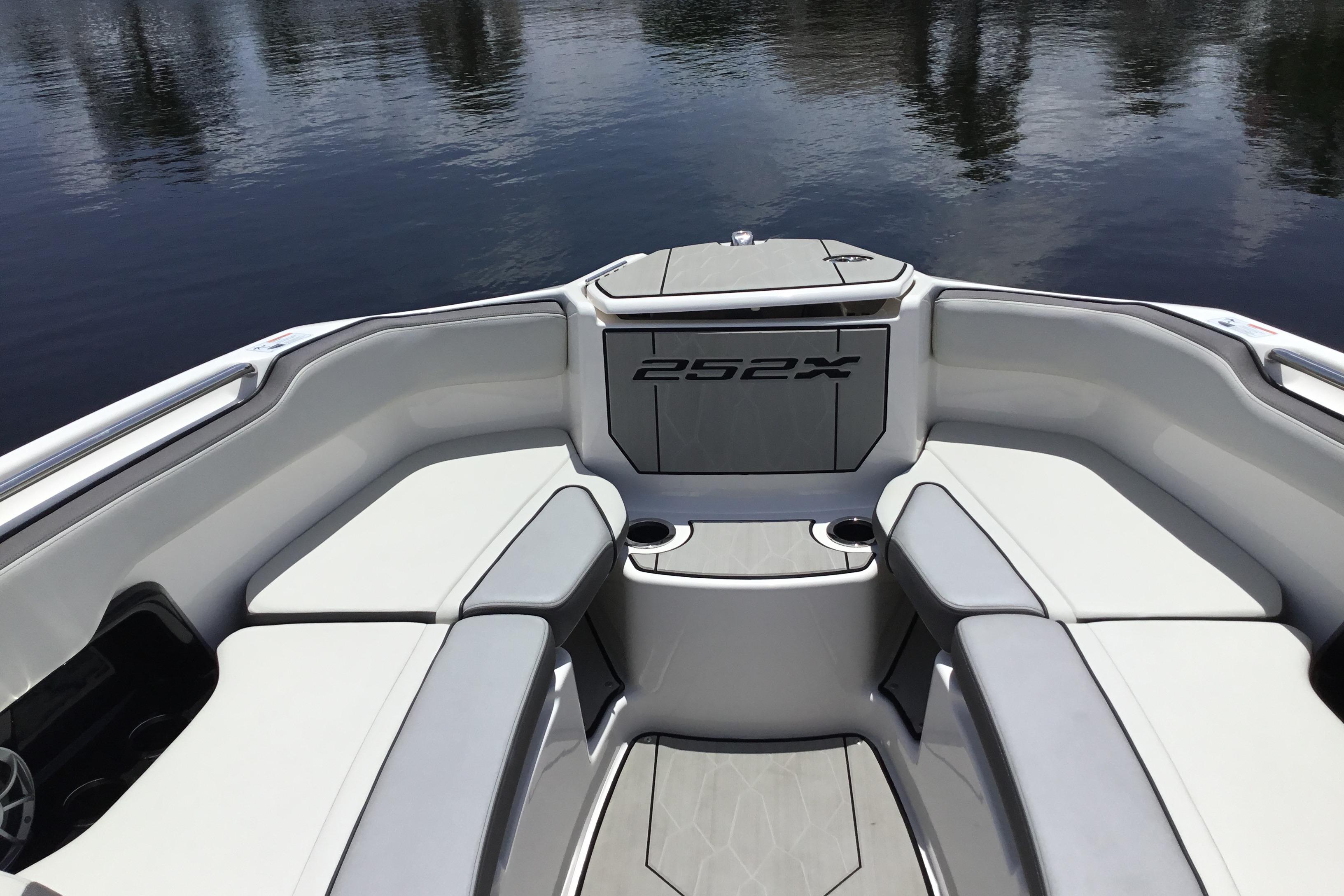 2023 Yamaha Boats 252XE interior with cushioned seating and cup holders on calm water.