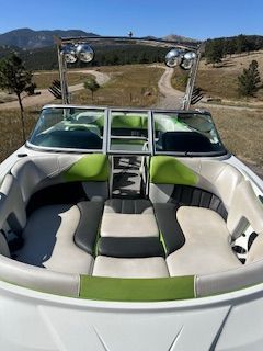 The boat features green and white upholstery, parked in a mountainous landscape.