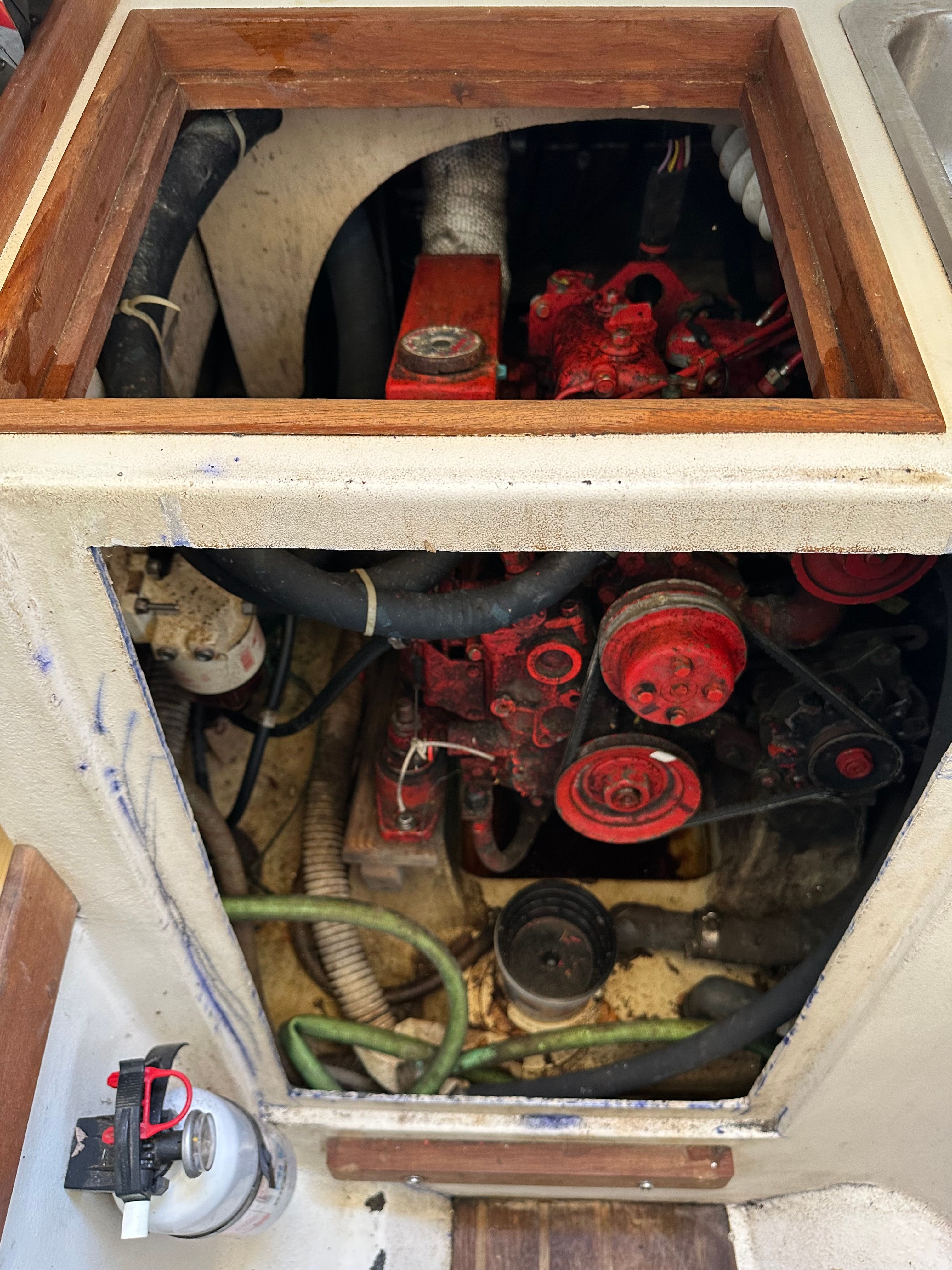Engine compartment of a 1985 Cape Dory 25D with a red engine and hoses.