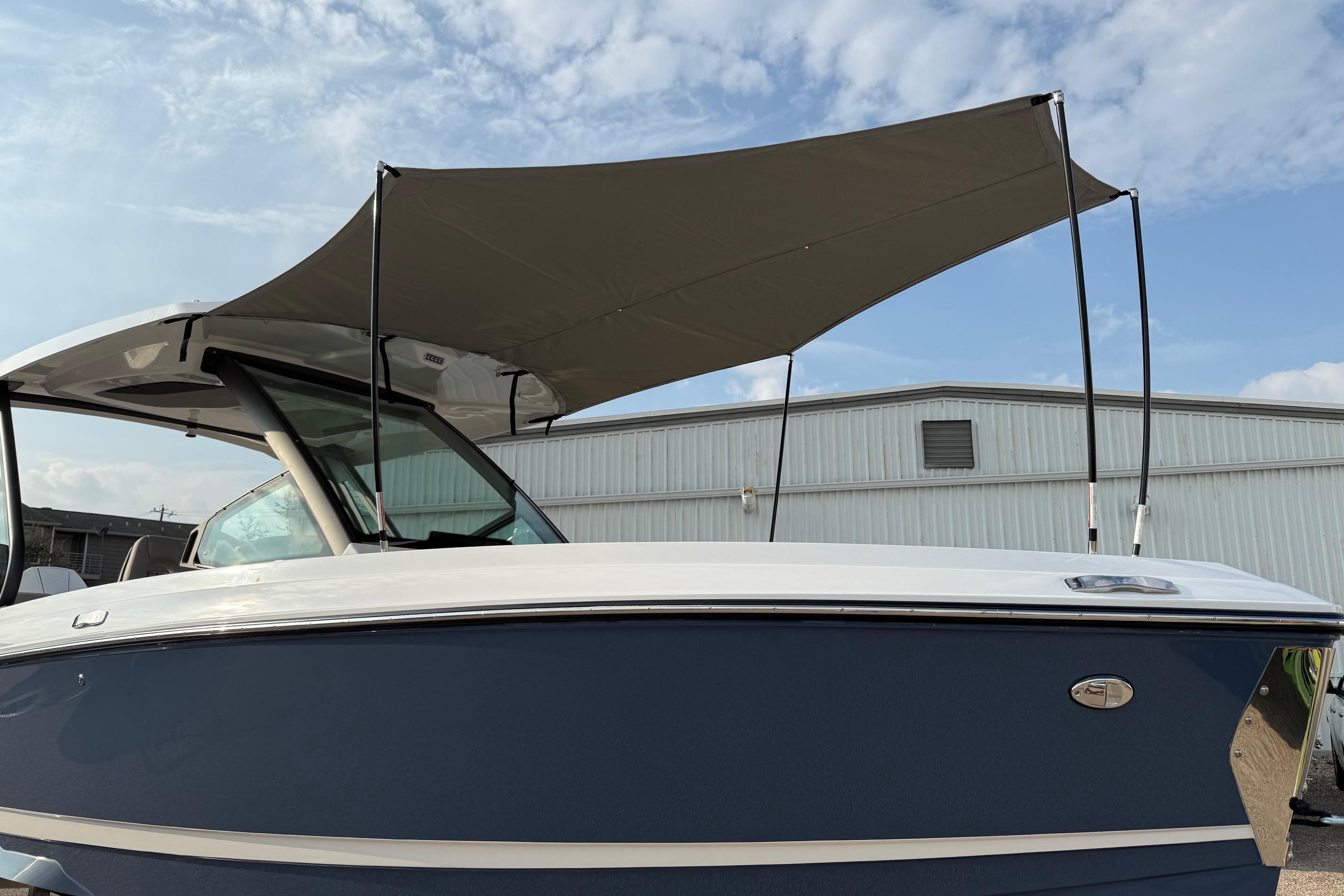 2026 Monterey Elite 25 OB boat with canopy, docked under a cloudy sky.