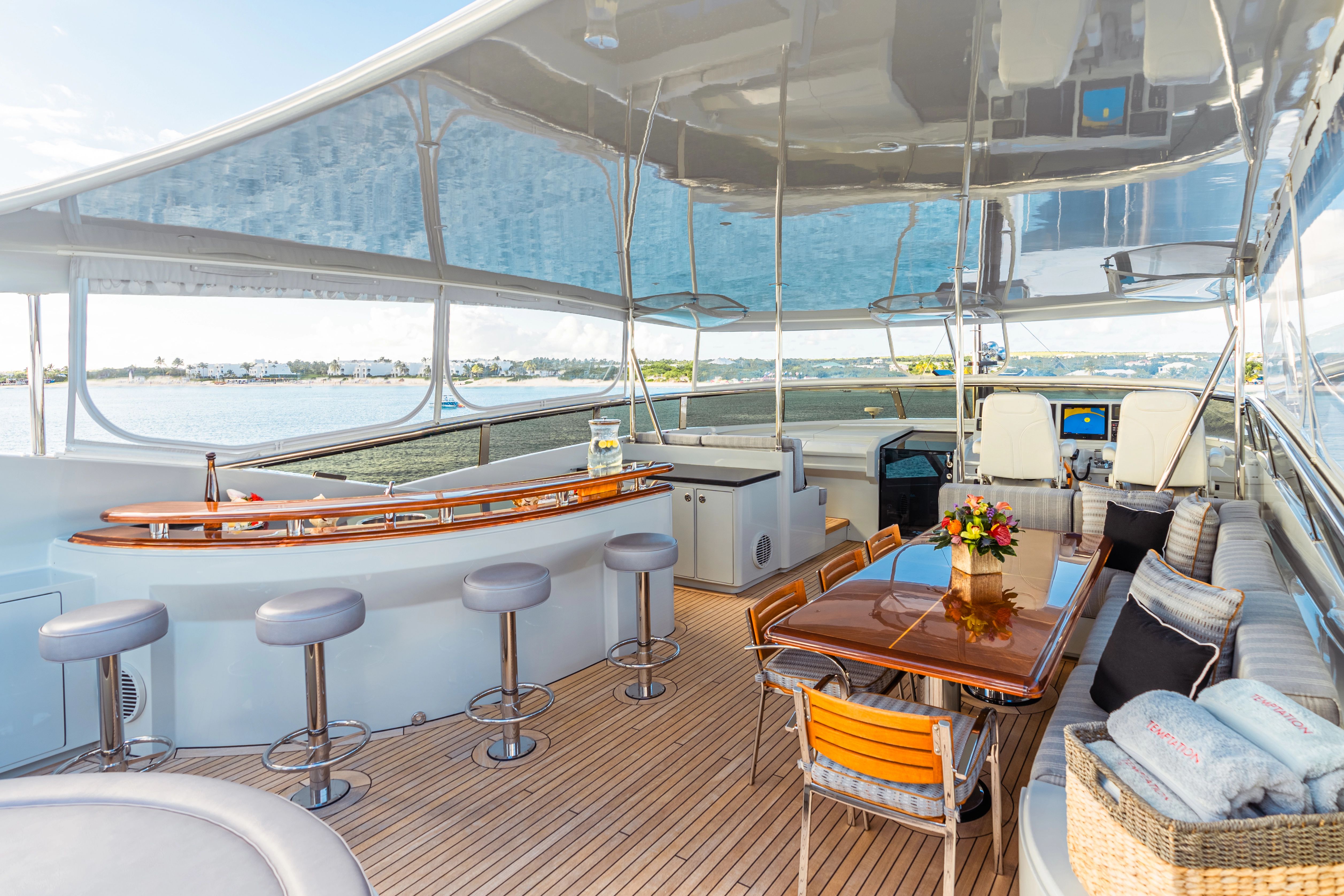 Luxurious yacht with a bar, dining table, and seating area on deck, surrounded by water.