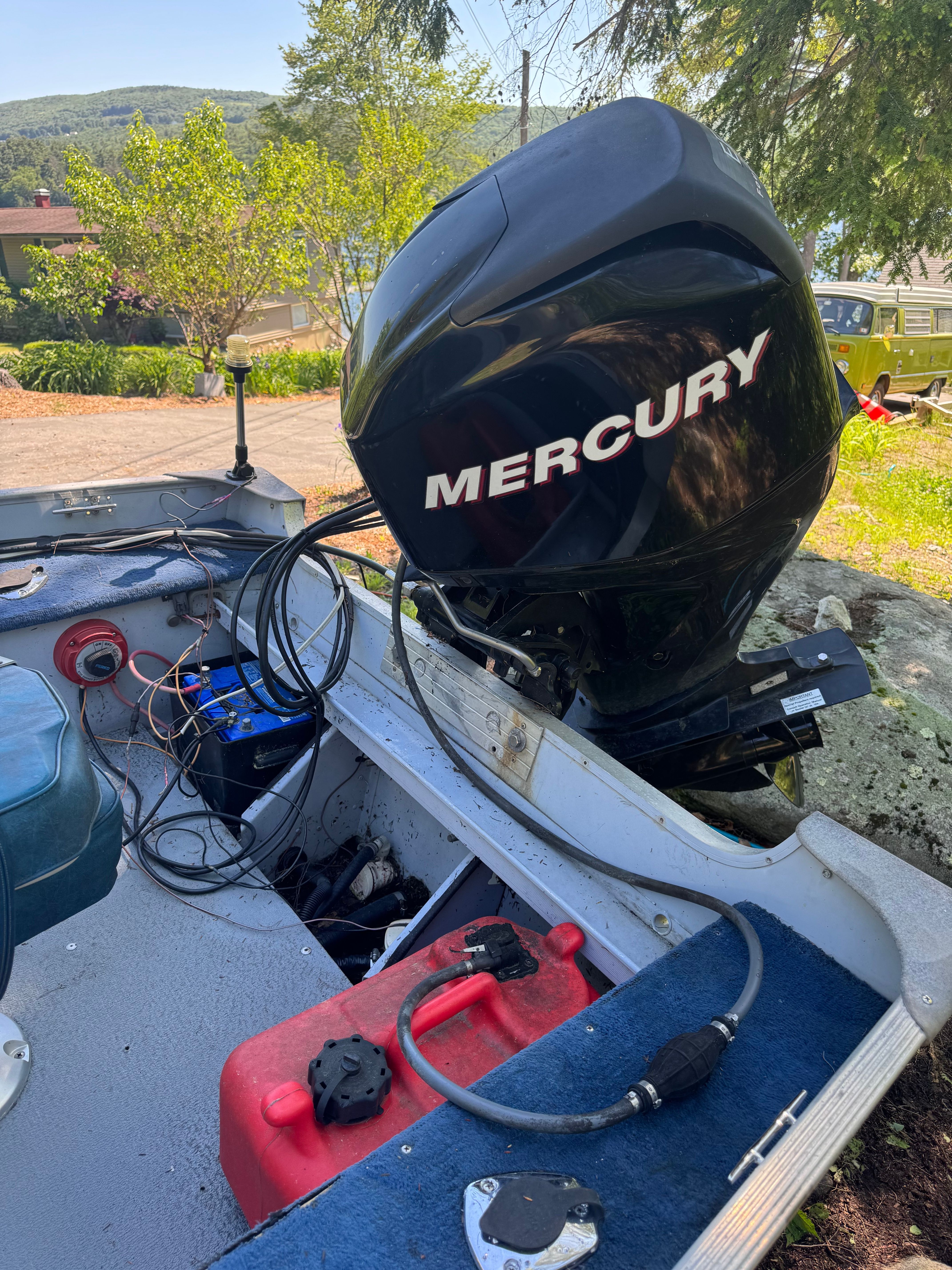 A boat with a Mercury outboard motor, parked on a trailer outdoors.