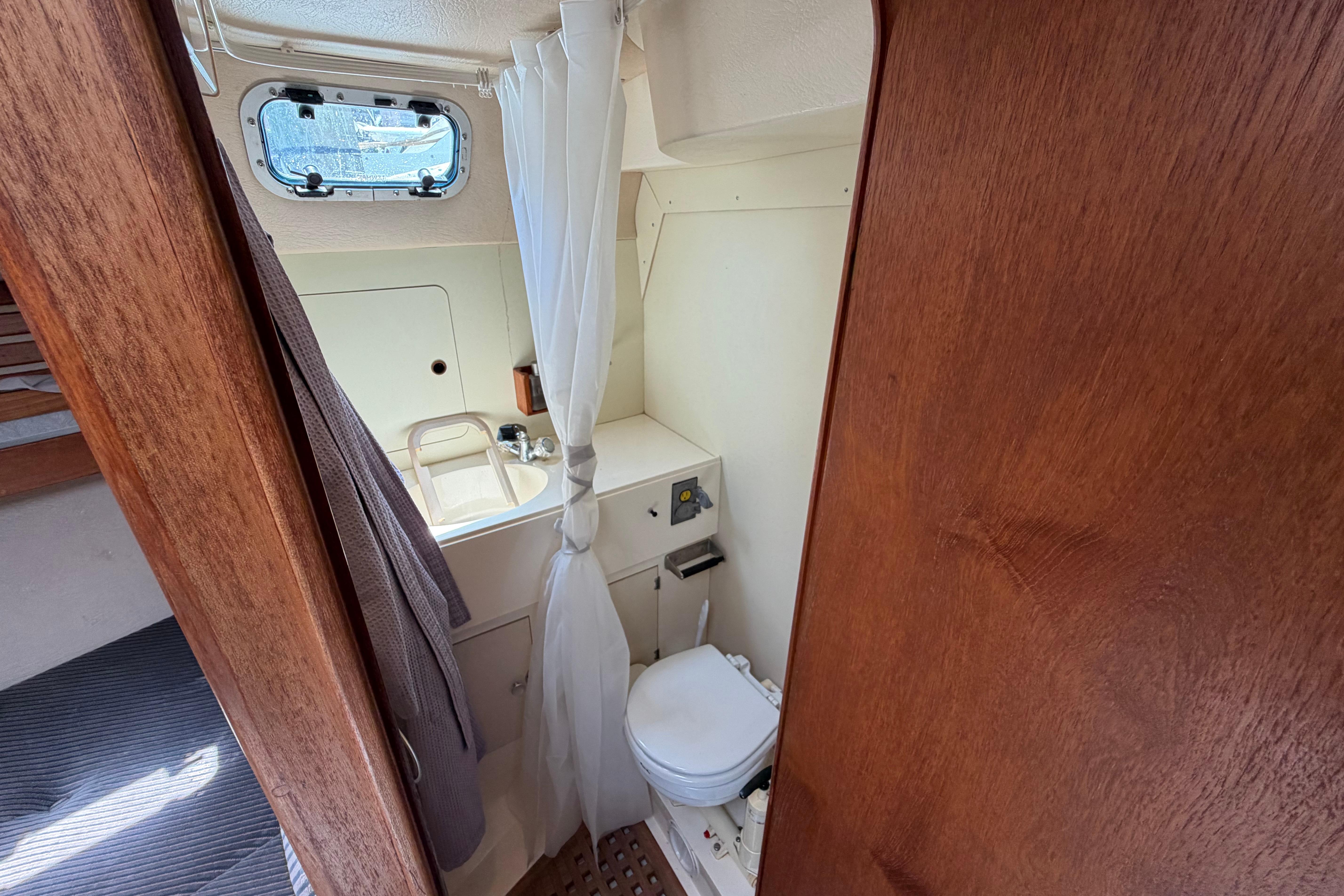 Compact bathroom in a 1987 Moody 376 sailboat, featuring a sink and toilet.