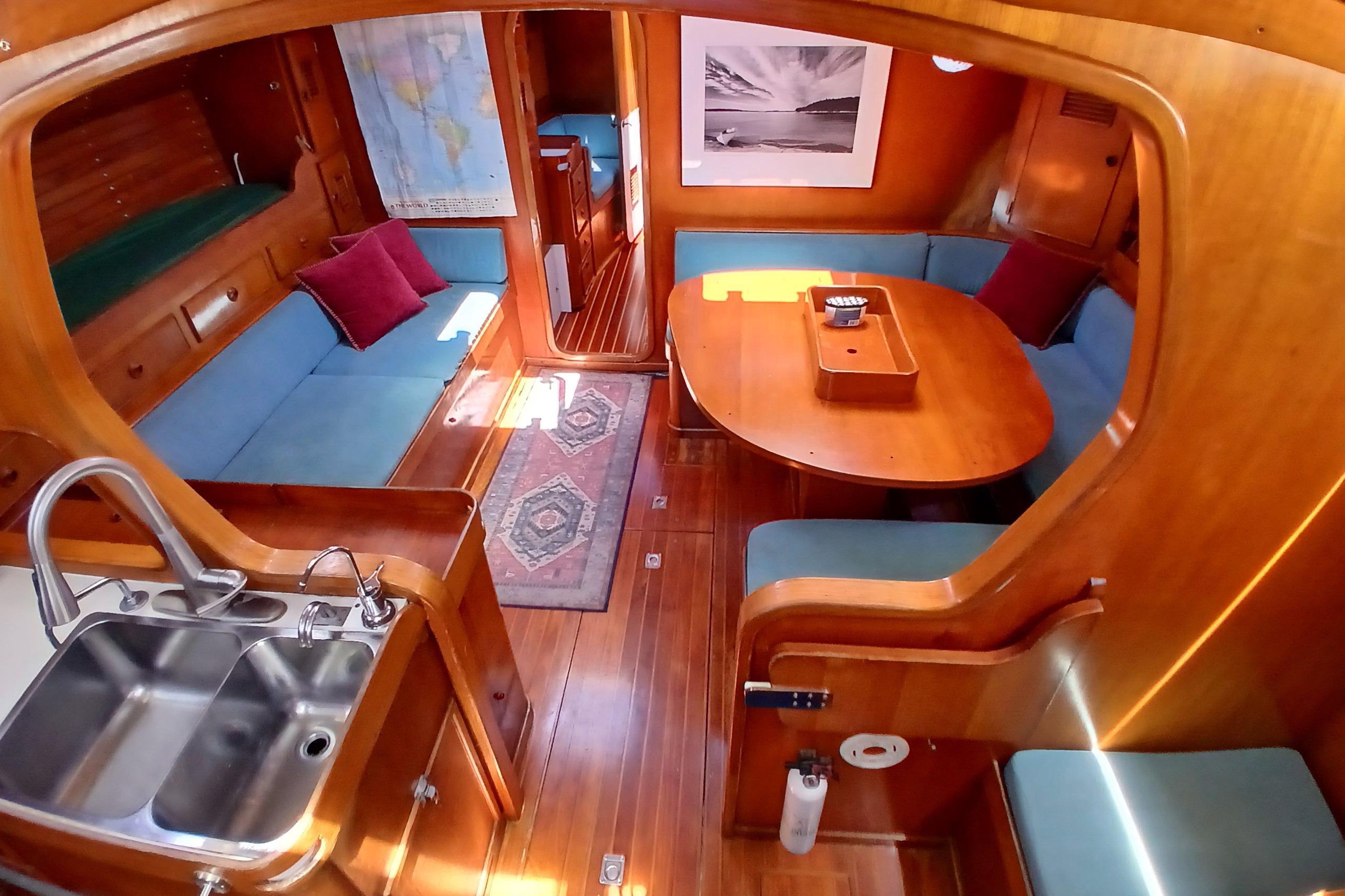 Interior of 1981 SKYE 51 yacht with wooden decor, blue seating, and kitchenette.
