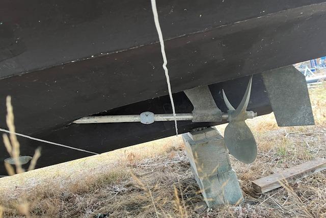 1981 Sea Ray Sundancer 310 boat underside with propeller and rudder on dry land.
