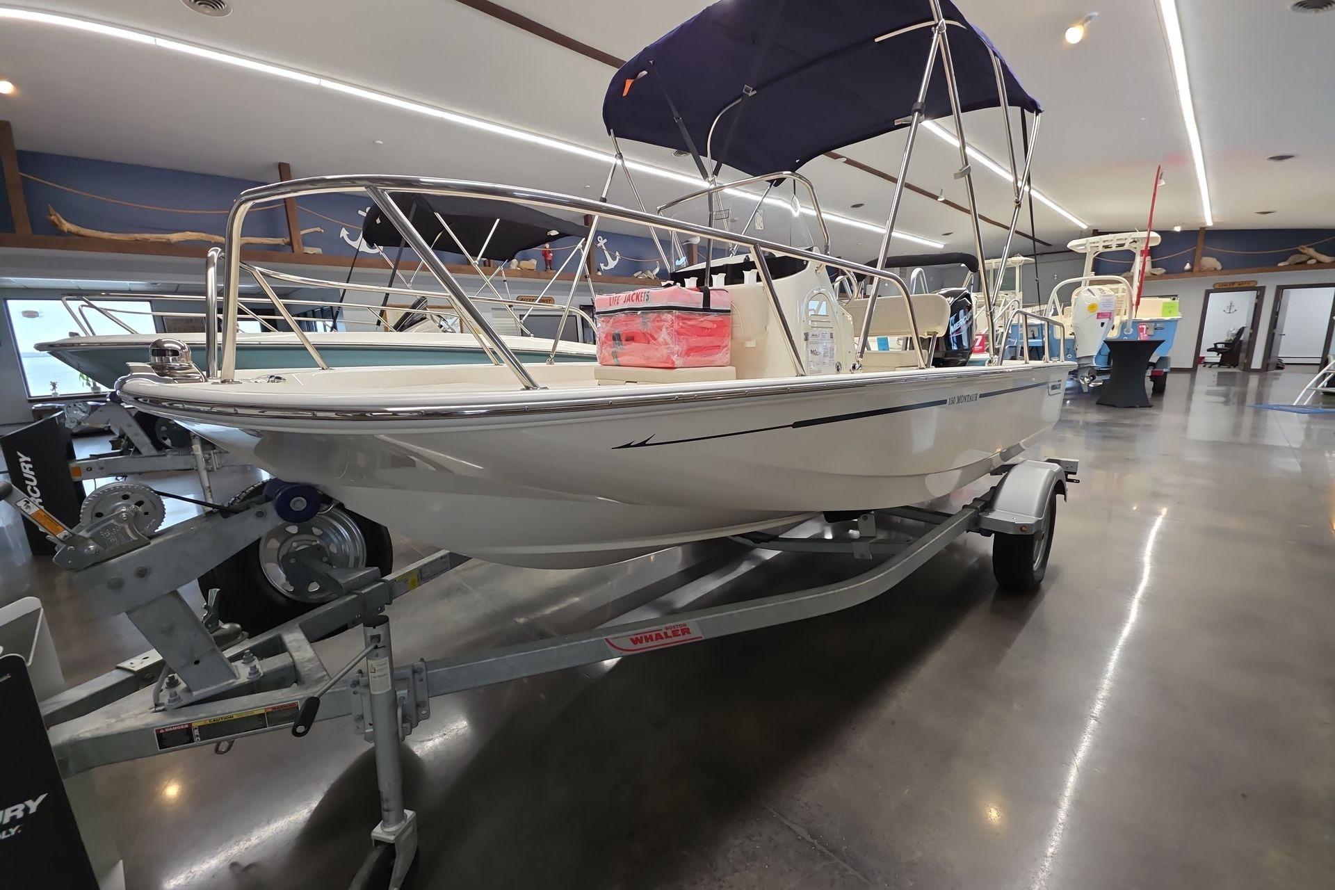 2026 Boston Whaler 150 Montauk boat displayed in a showroom on a trailer.