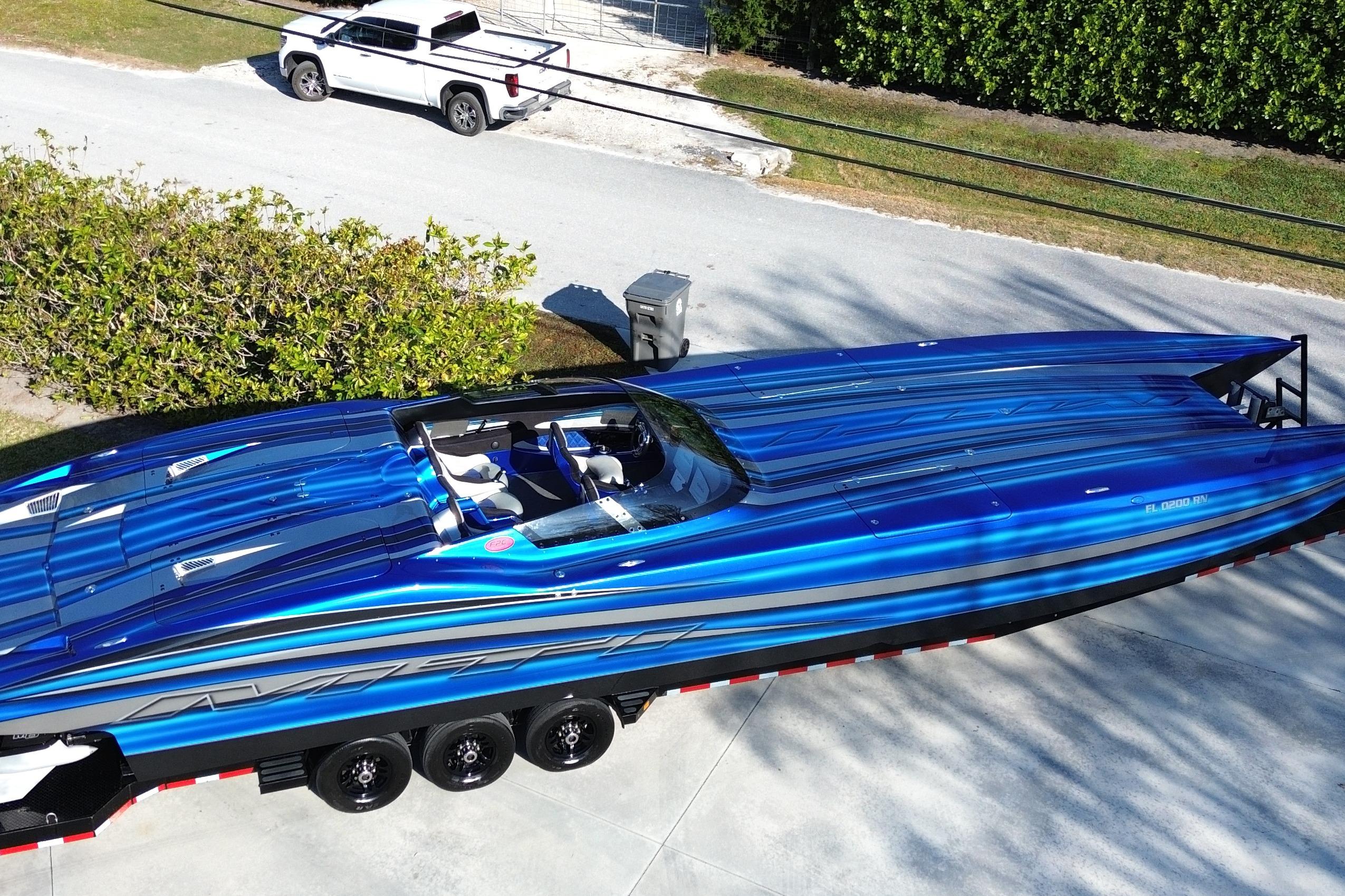 Blue 2016 MTI 44 RP speedboat on trailer, parked near a white truck.