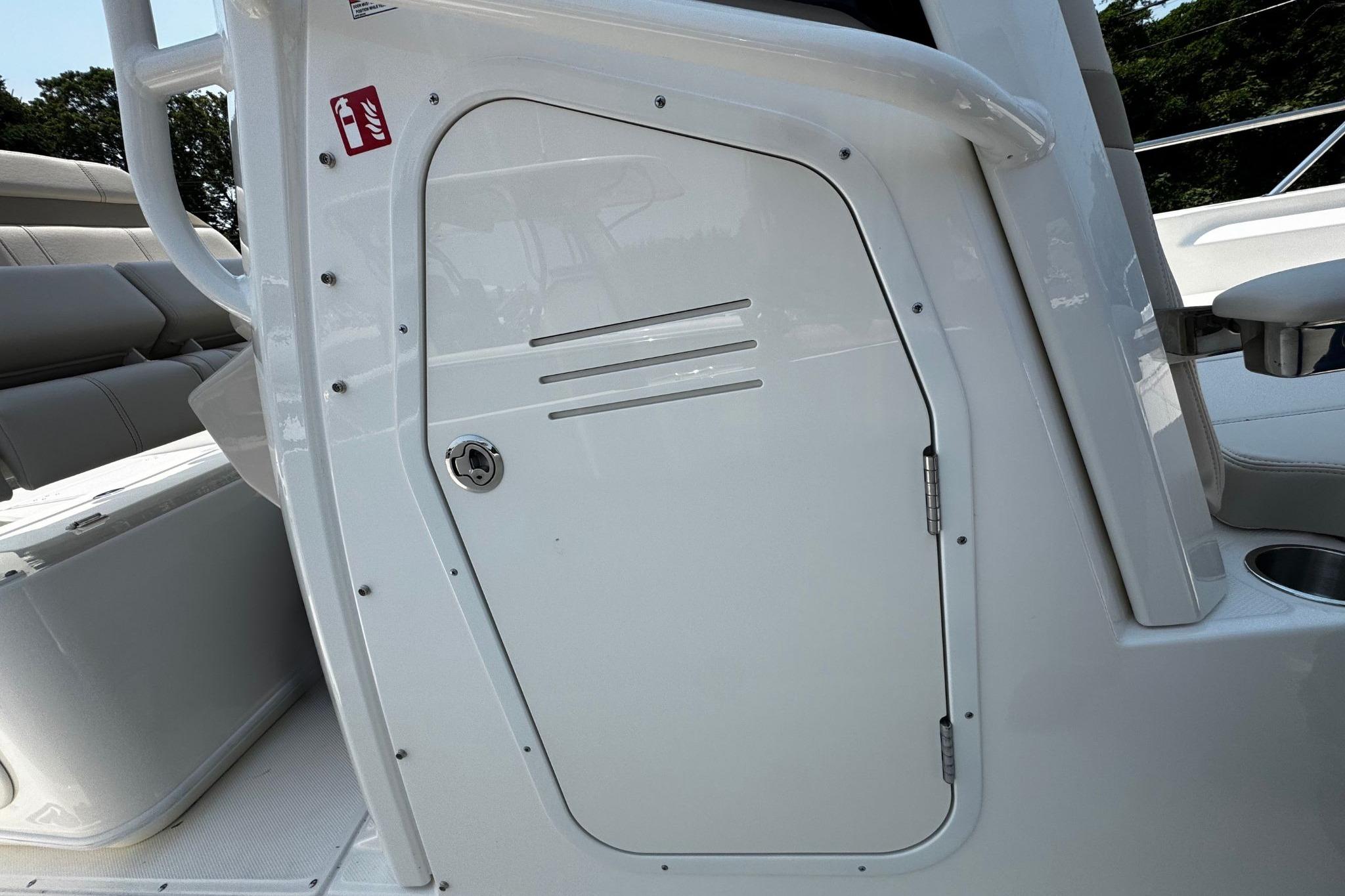 2026 Boston Whaler 220 Dauntless boat console door with fire extinguisher sign.