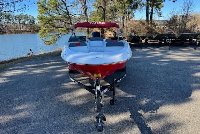 2026 Tahoe T16 boat on trailer by a lakeside, surrounded by trees.