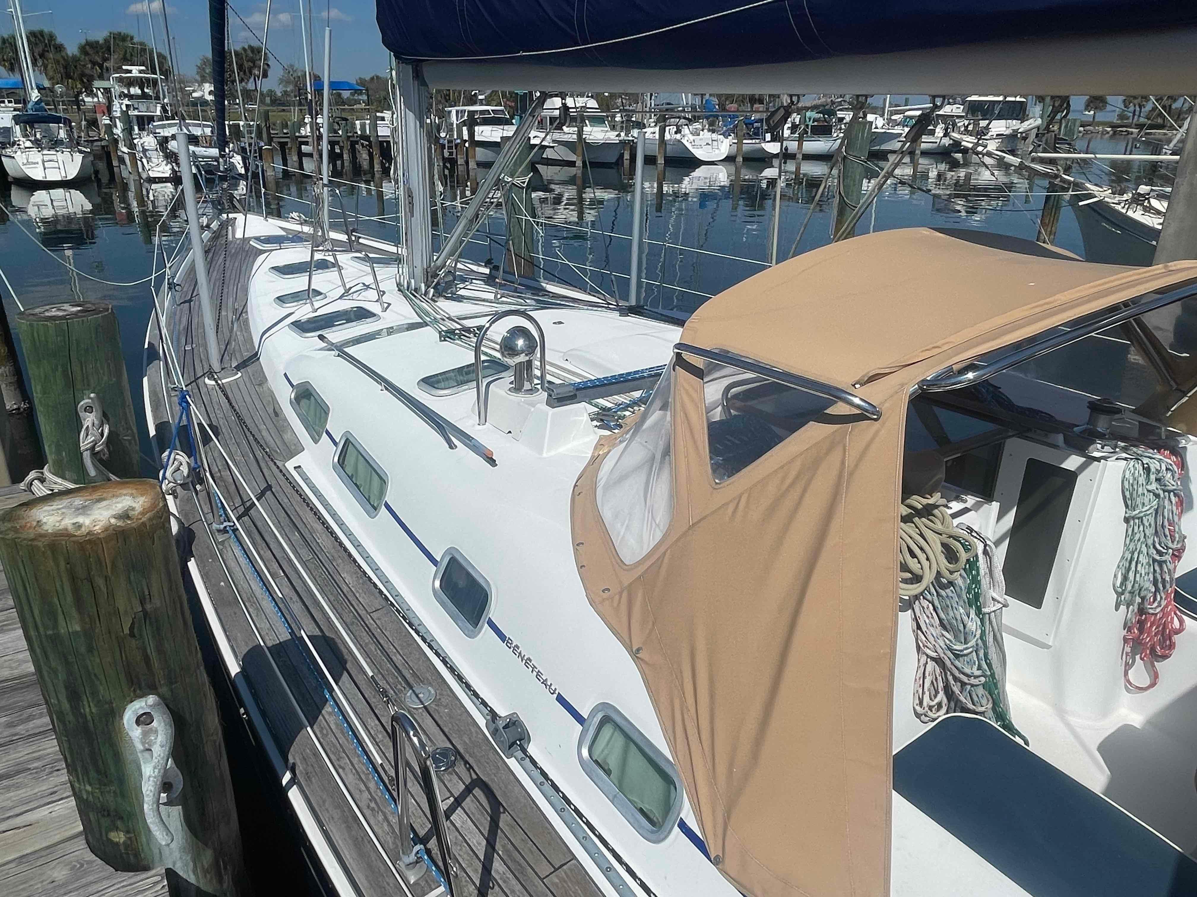2004 Beneteau Oceanis 473 sailboat docked at a marina, featuring a beige canopy.