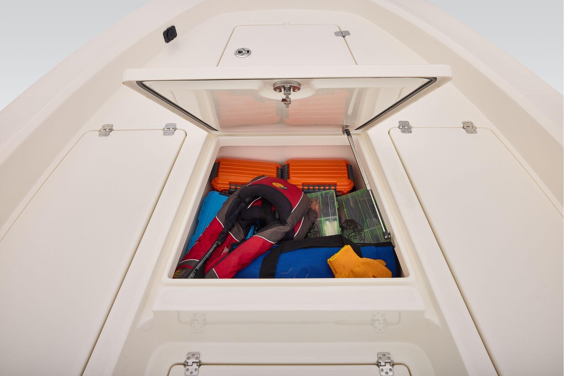 Open storage compartment on 2026 Mako 24 APEX boat with safety gear and equipment.