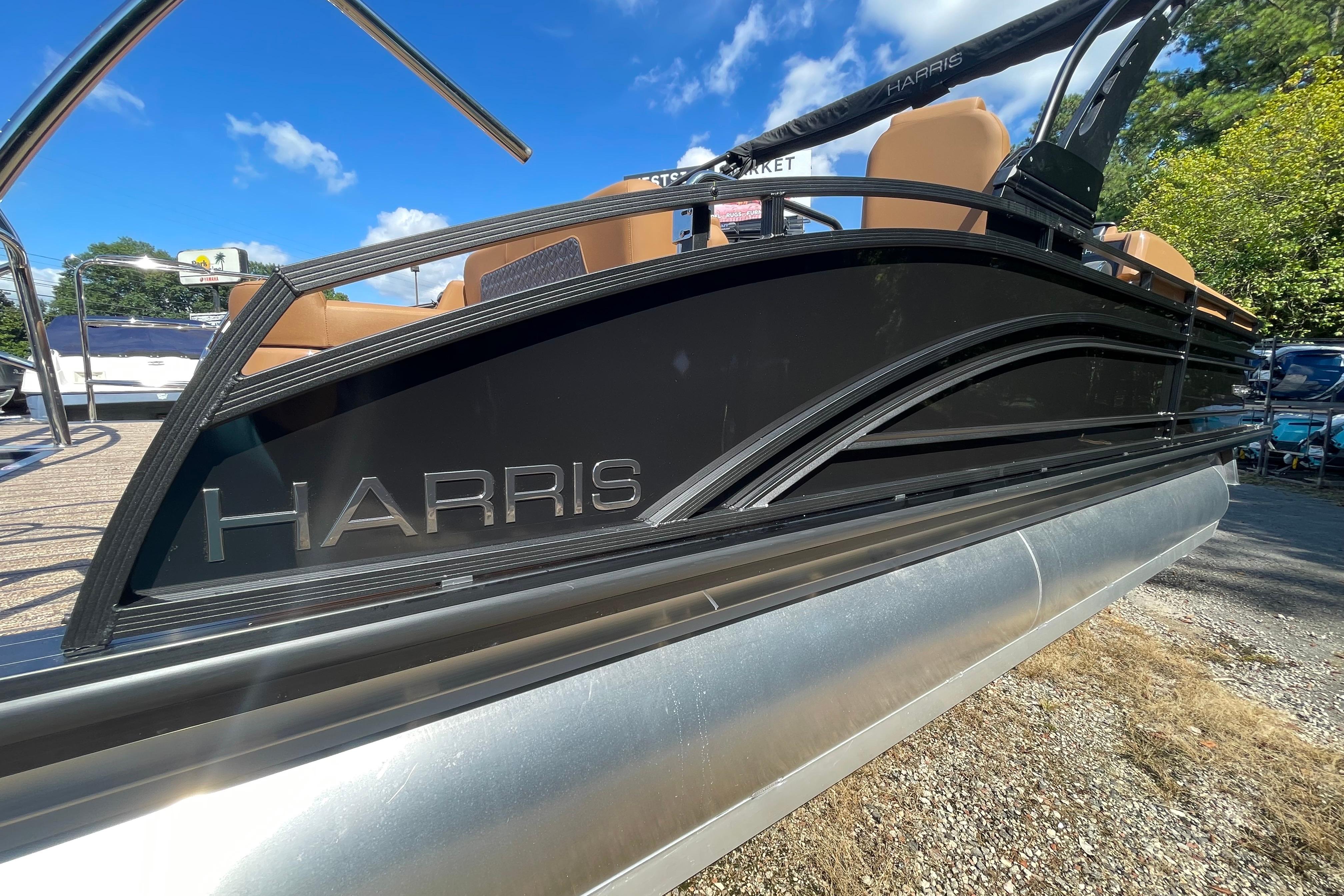 2026 Harris Solstice 250 SLDH pontoon boat with sleek black design under a clear blue sky.