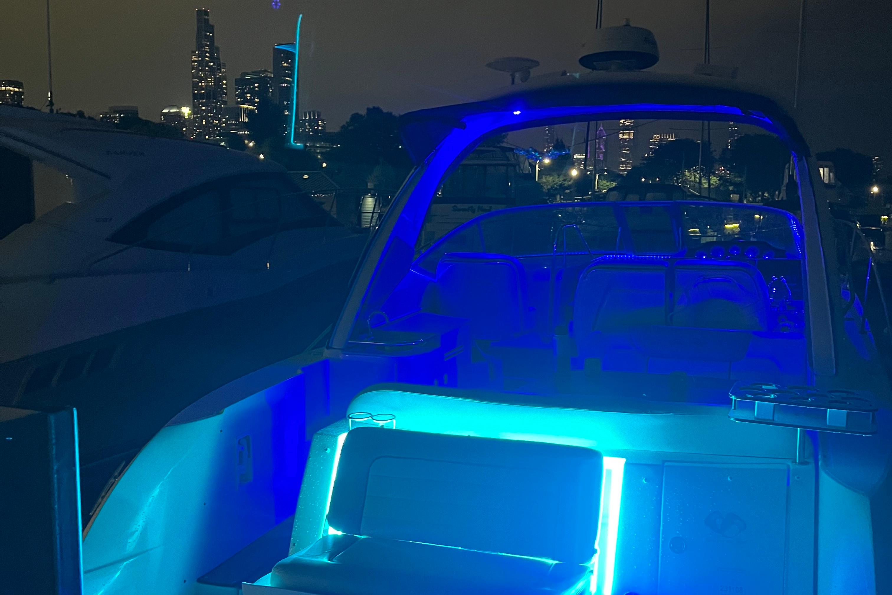 2008 Sea Ray 350 Sundancer yacht illuminated with blue lights at night, city skyline in background.
