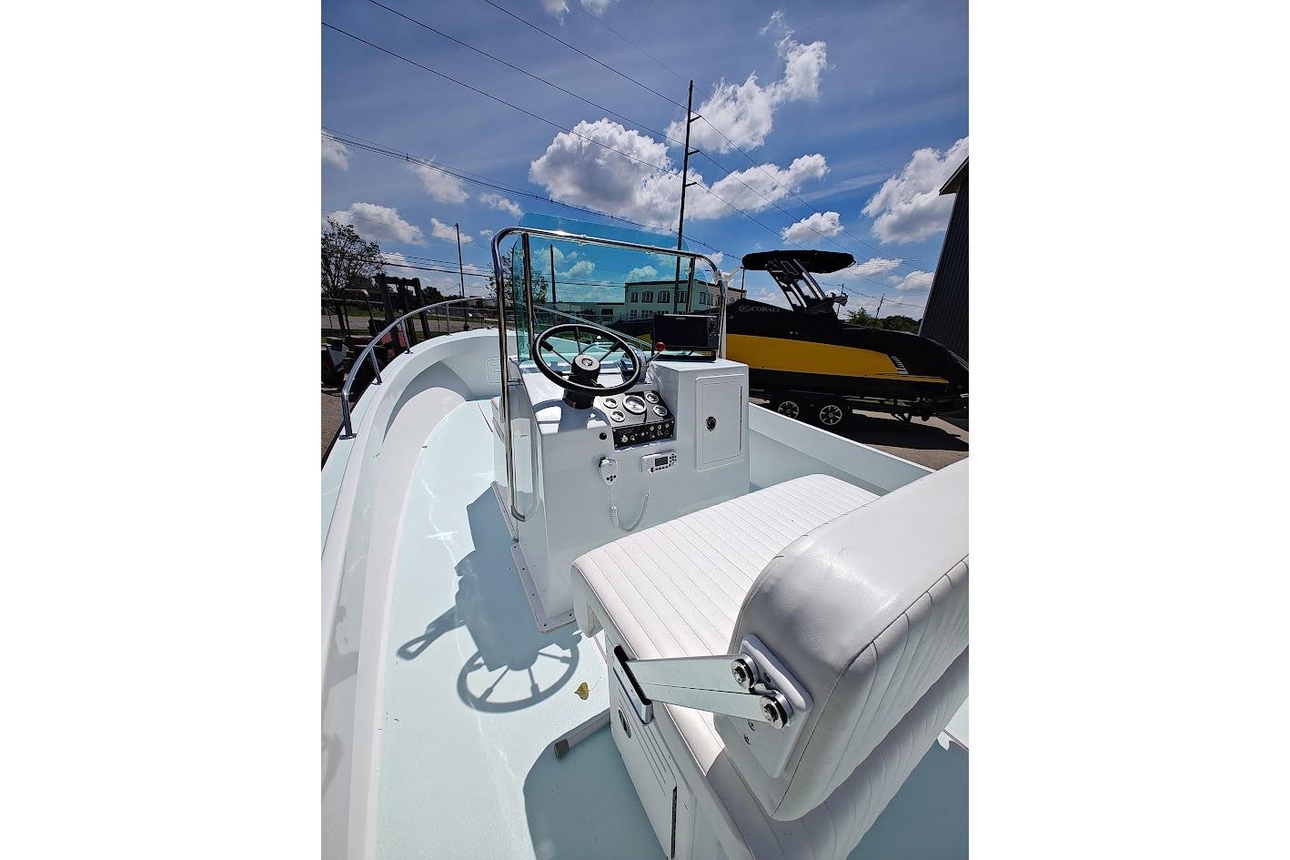1975 Shamrock 200 Open boat interior with steering wheel and seating under a blue sky.