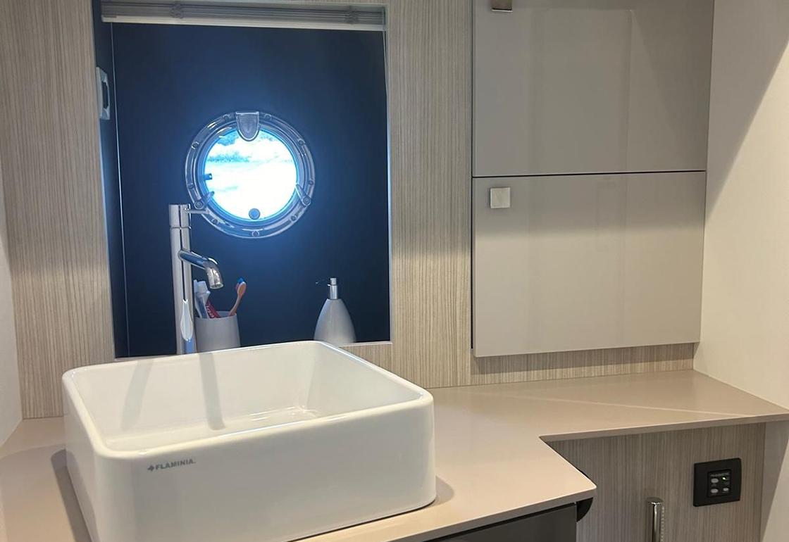 Modern bathroom interior on 2020 Cranchi 60 ST yacht with porthole and sleek sink design.