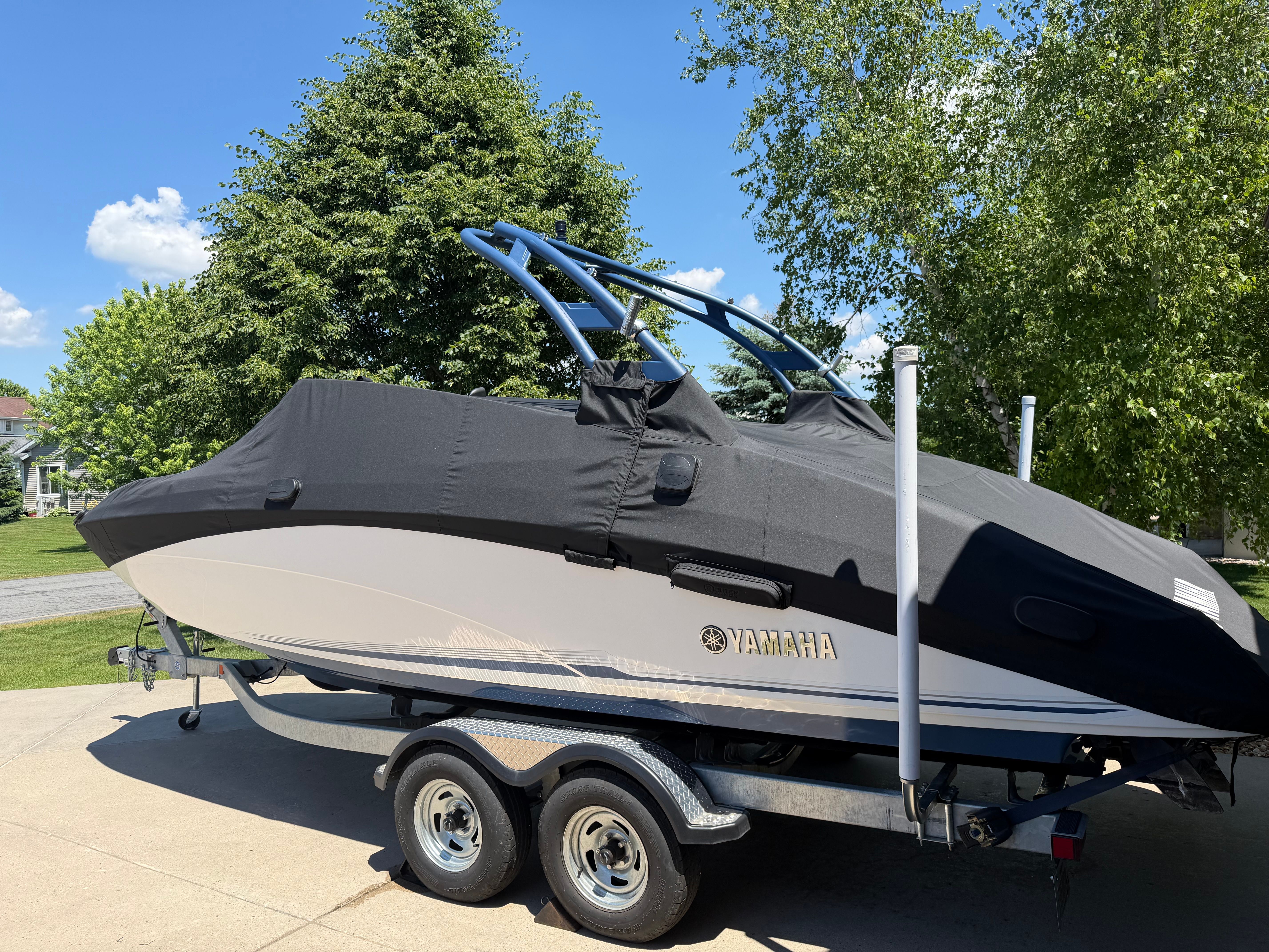 A 2018 Yamaha 242 Limited S boat on a trailer, covered with a black cover.