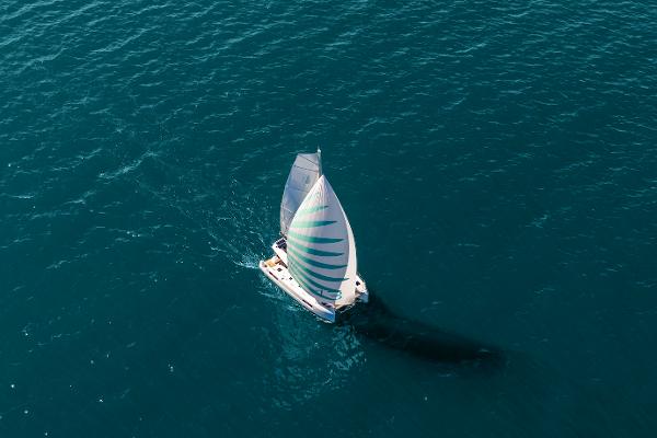 Aerial view of 2025 Lagoon 43 sailboat navigating open sea with full sails.