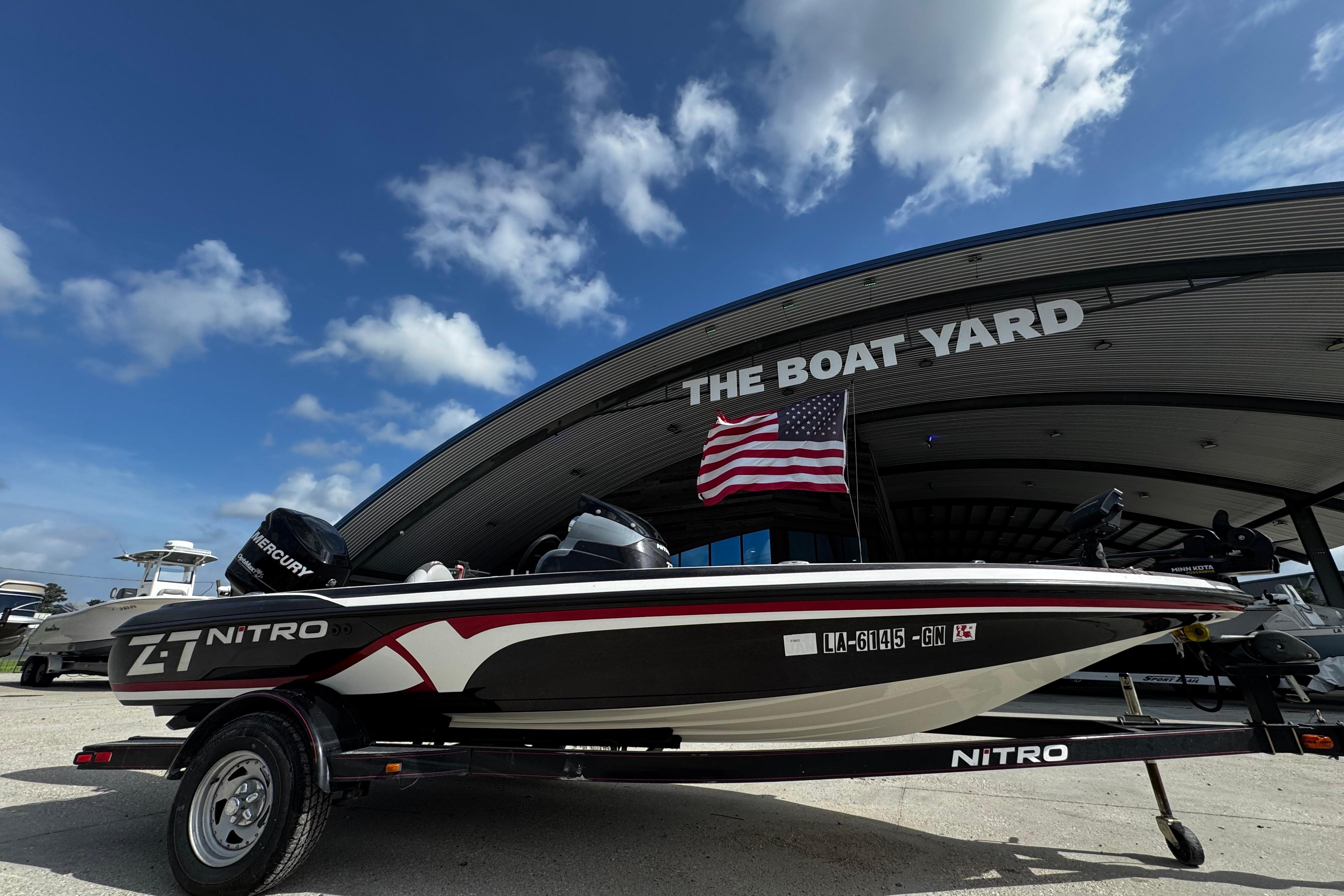 2012 Nitro Z-7 boat at dealership with American flag and Mercury engine.