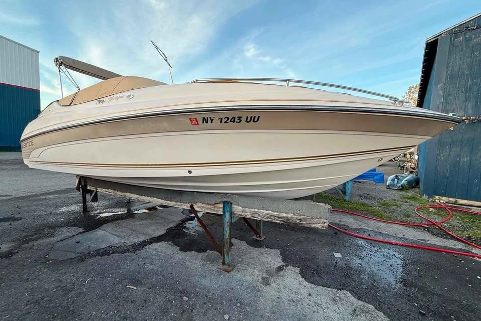 1999 Ebbtide 2300 Bow Rider boat on a stand, side view, outdoors.