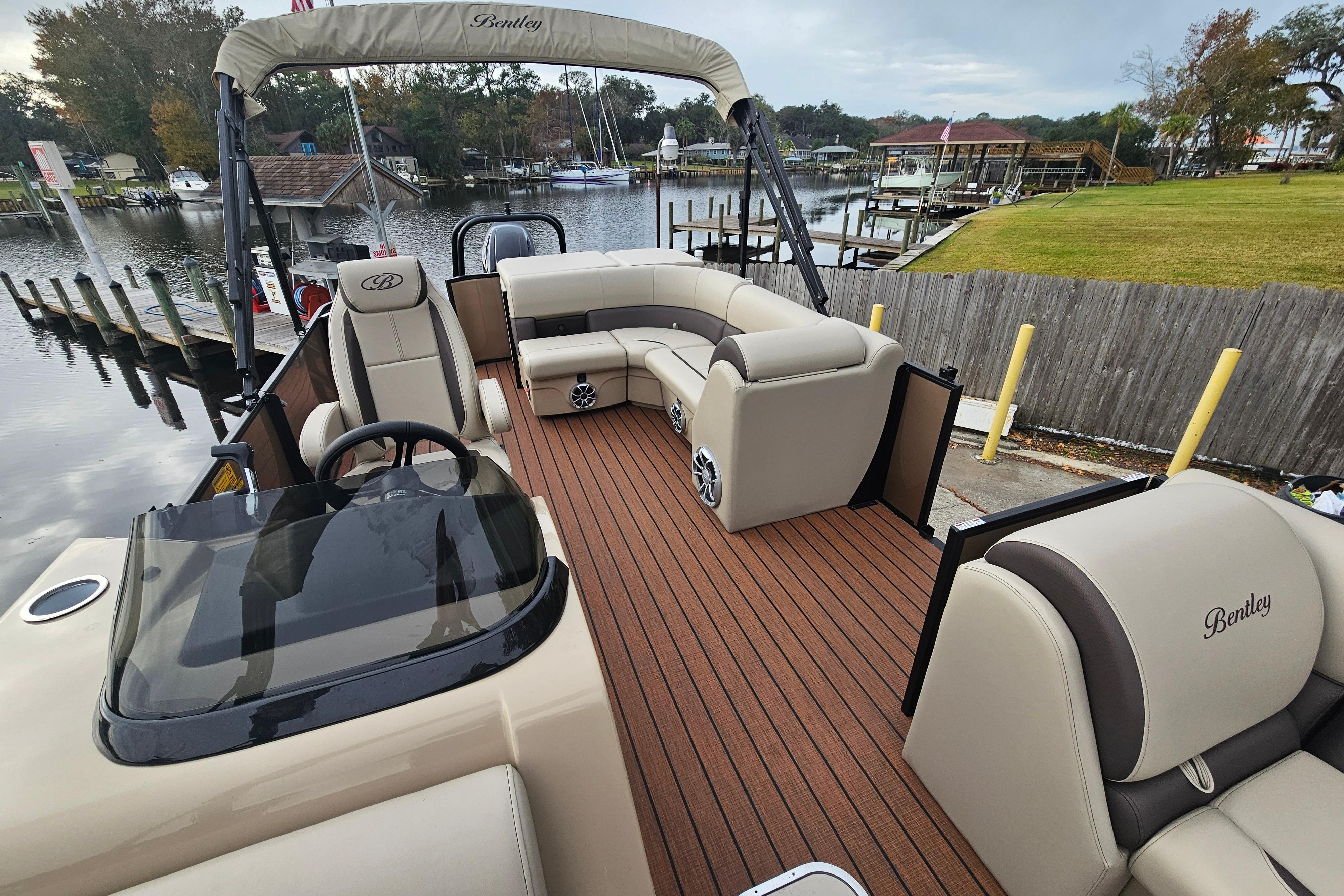 2026 Bentley Pontoons Legacy 243 Cruise with luxurious seating and sleek design on a scenic dock.