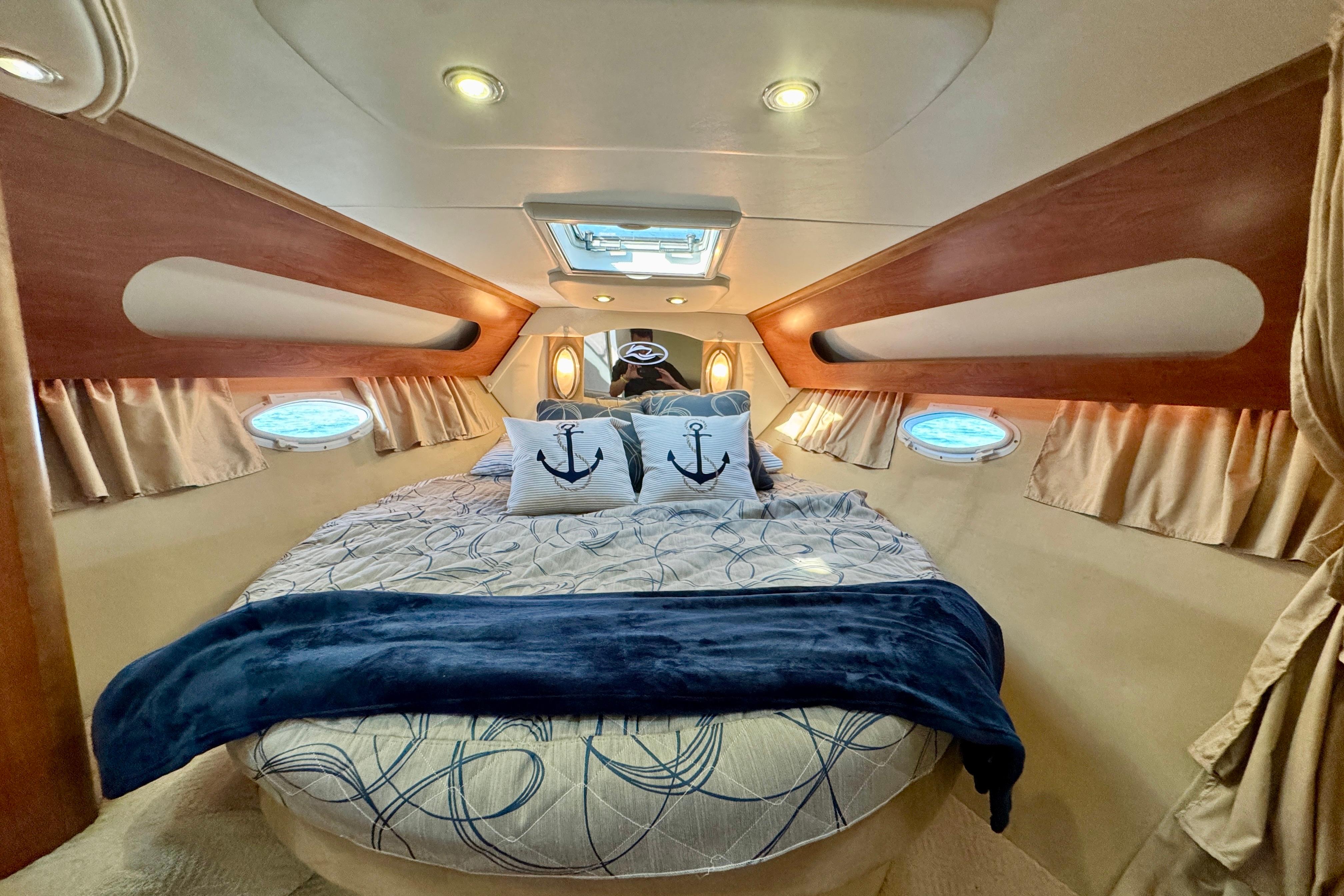 Luxurious 2009 Rinker 360 Express Cruiser cabin with cozy bedding and nautical decor.