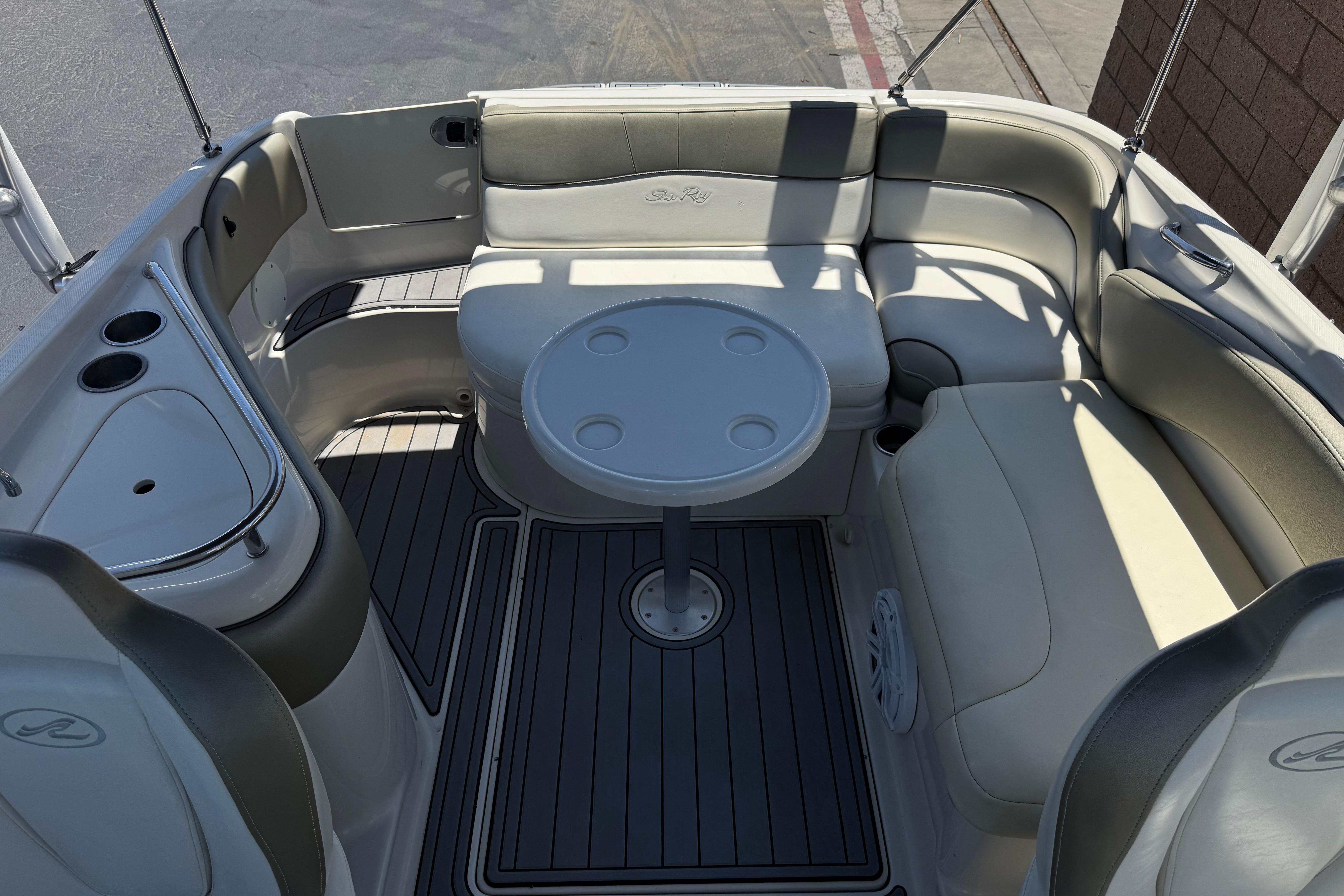 2007 Sea Ray 240 Sundeck interior with seating and table, featuring cup holders.