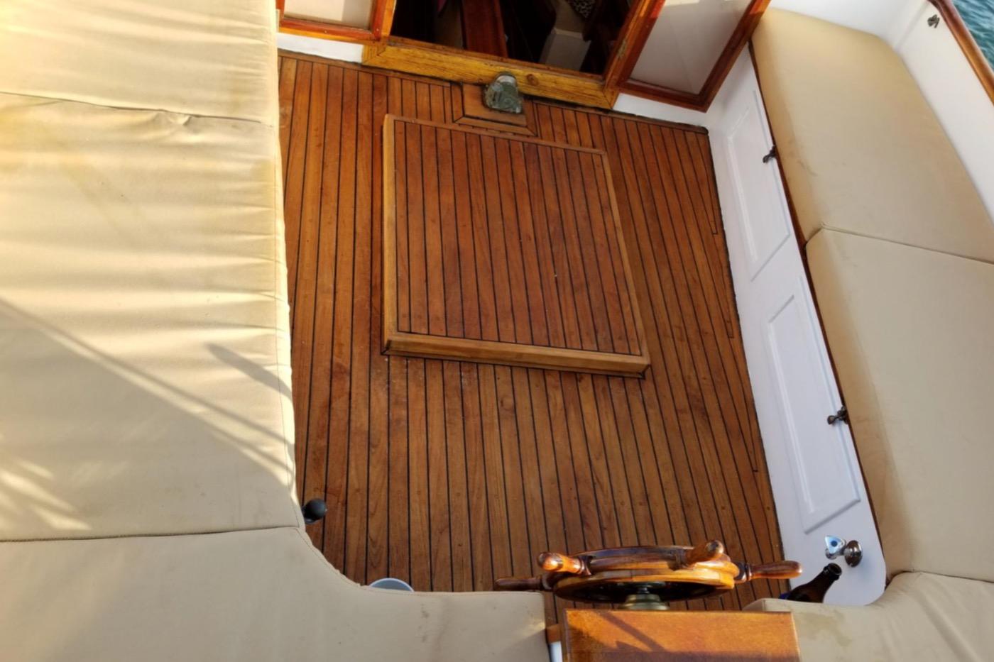 1978 Cape Cod Catboat interior with wooden deck and cushioned seating.