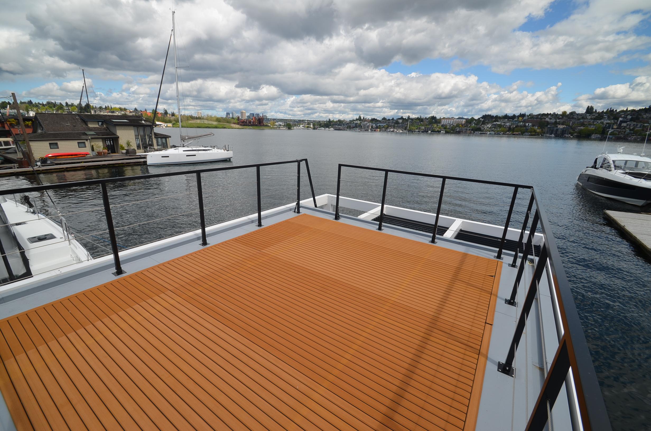 Rooftop deck of 2024 La Mare Modern 11 houseboat overlooking serene lake and marina.