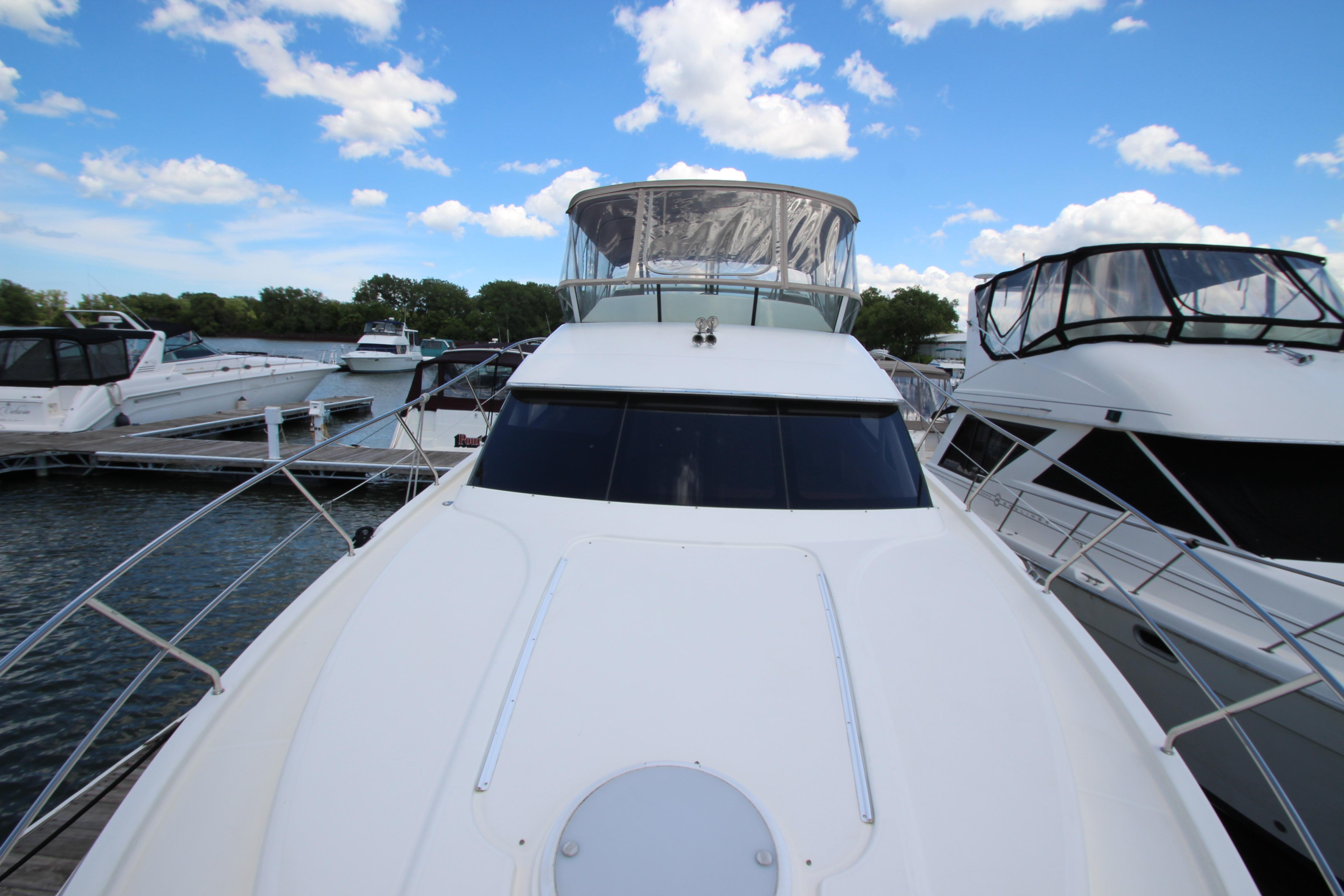 2006 Silverton 38 Sport Bridge yacht docked at marina under blue sky.
