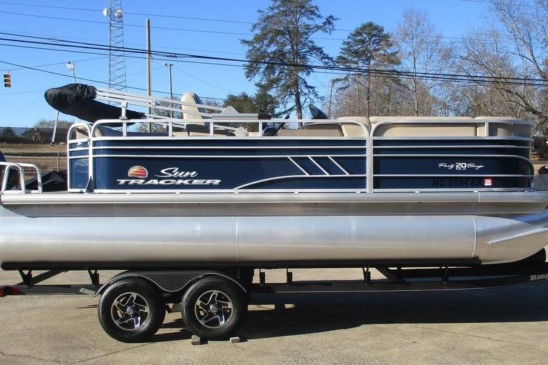 2022 Sun Tracker Party Barge 20 DLX pontoon boat on trailer, parked outdoors.