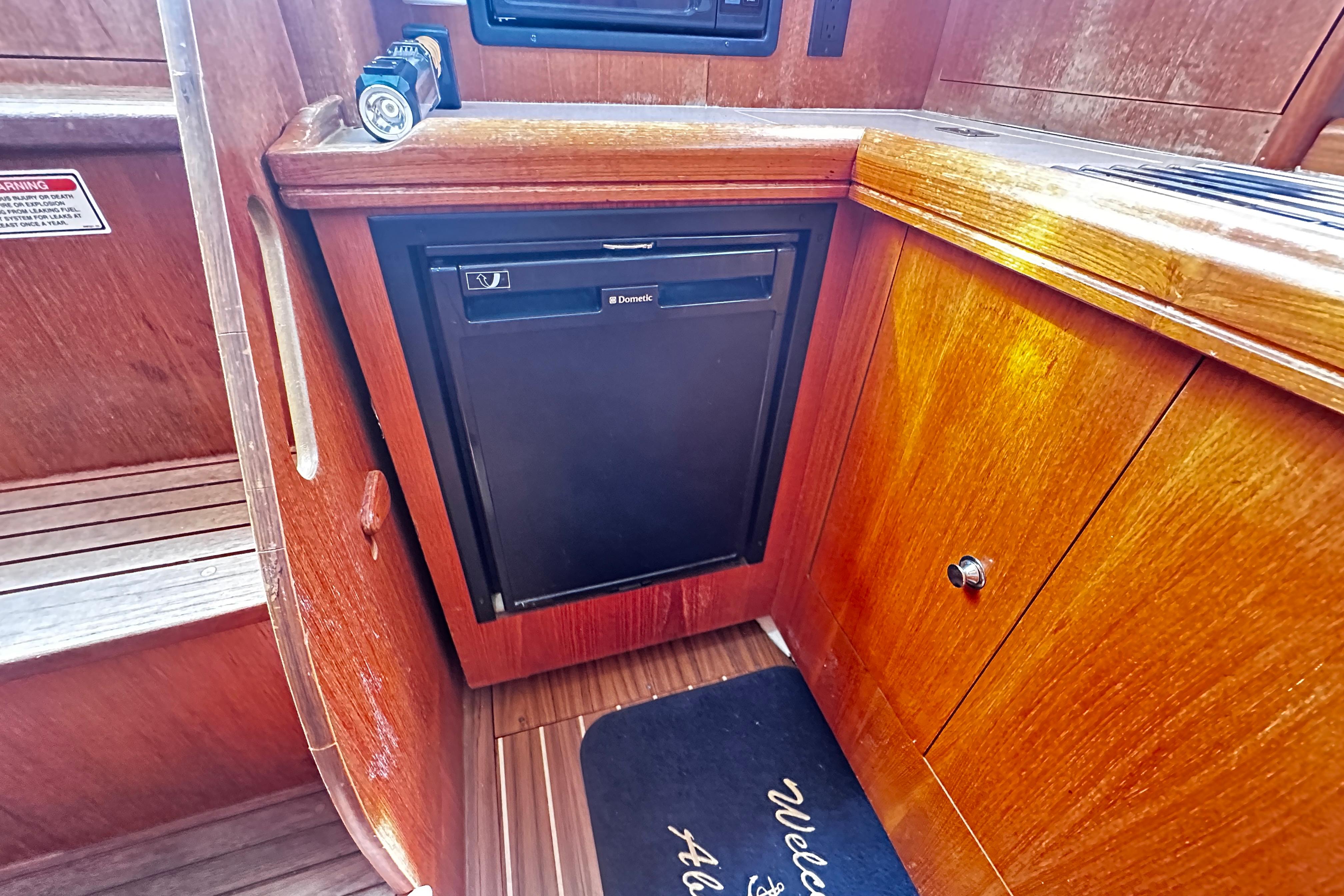 2004 Hunter 33 yacht interior with wooden cabinetry and compact Dometic fridge.