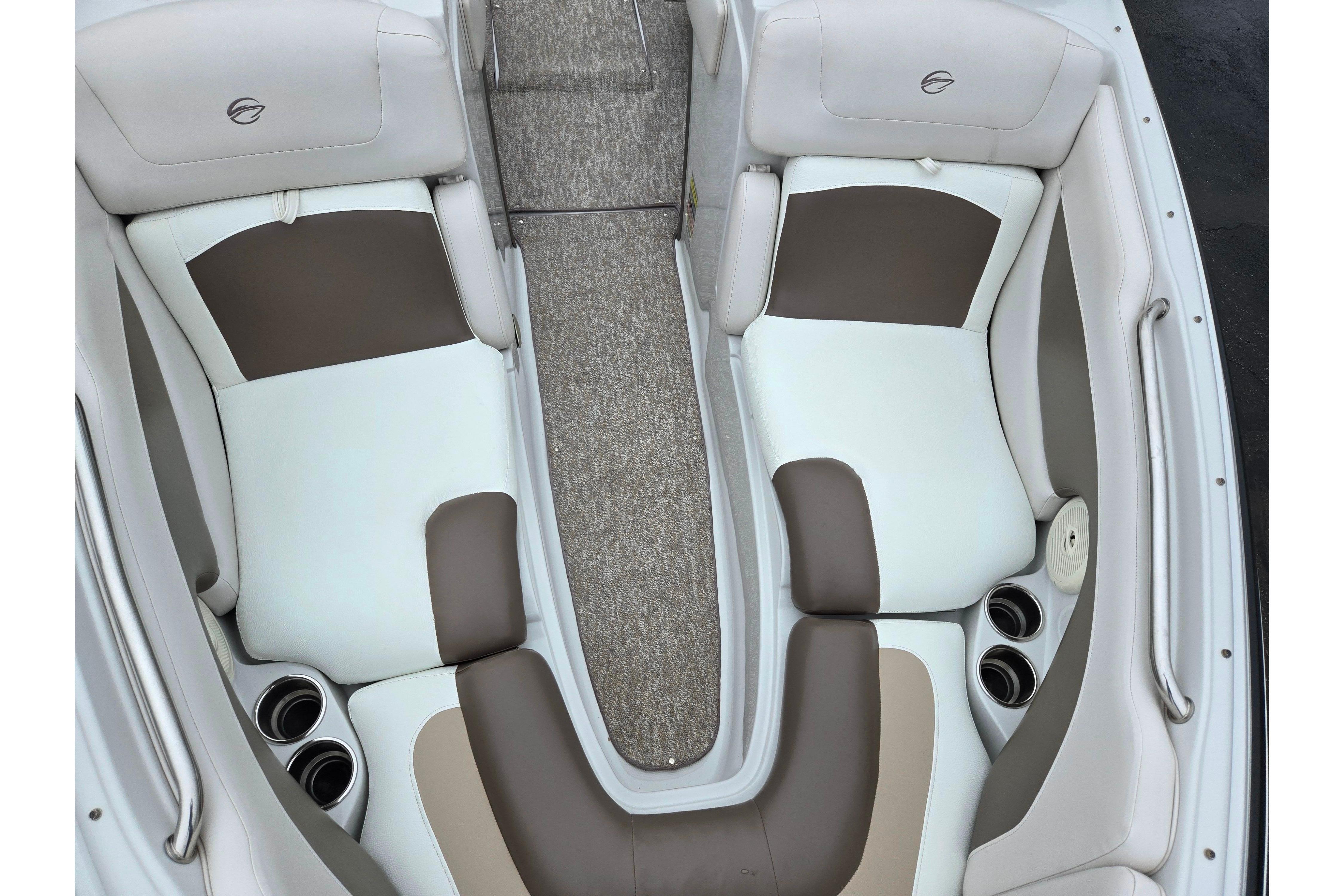 2012 Crownline 235 SS boat interior with beige and white seating, cup holders, and carpeted flooring.
