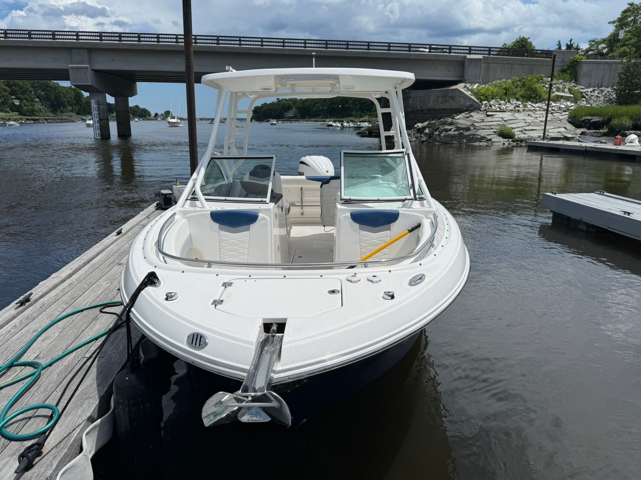 Robalo R247 Dual Console 2022 at a dock, surrounded by calm water and a bridge.