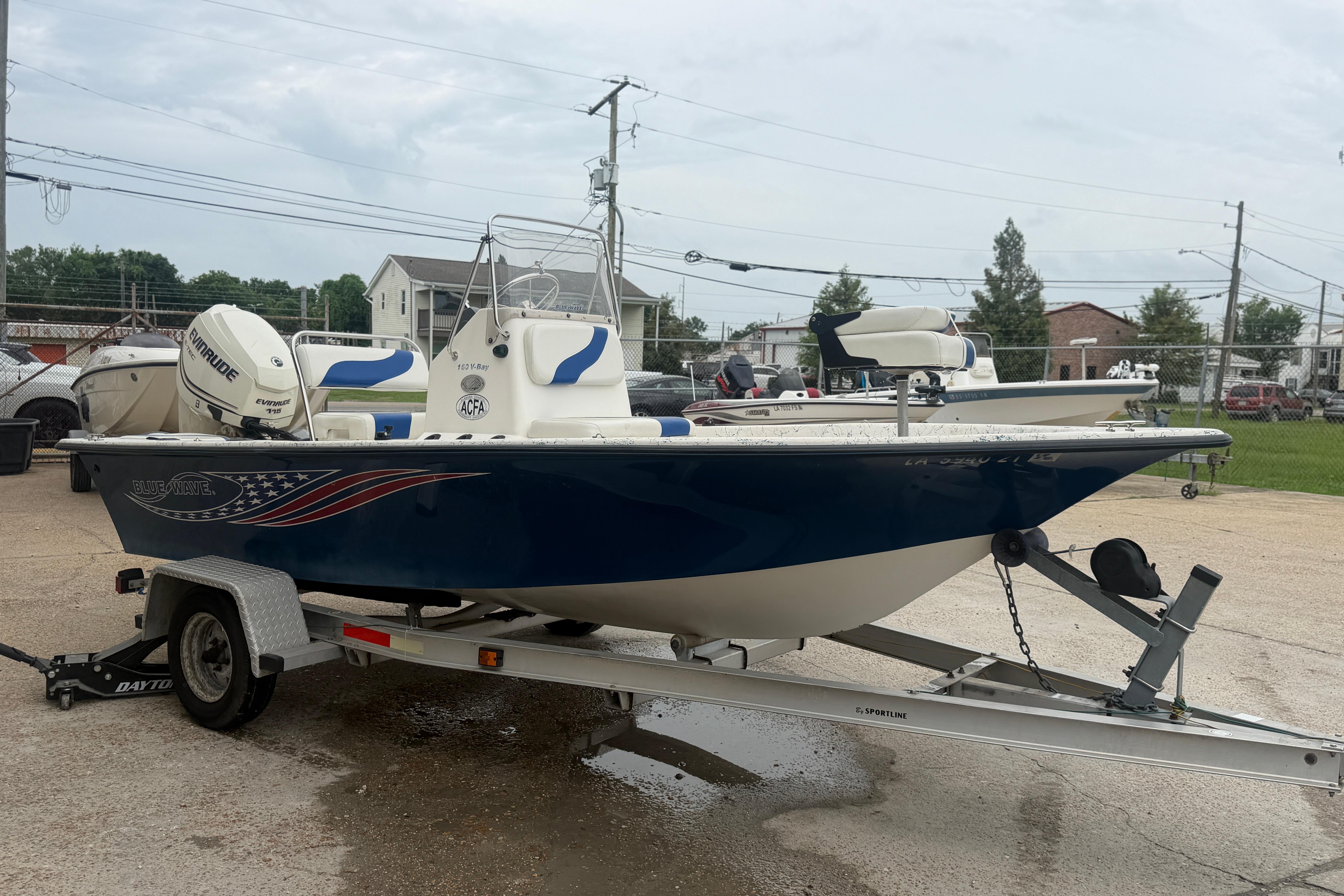 2004 Blue Wave 160 V-Bay boat on trailer, featuring Evinrude engine, parked outdoors.
