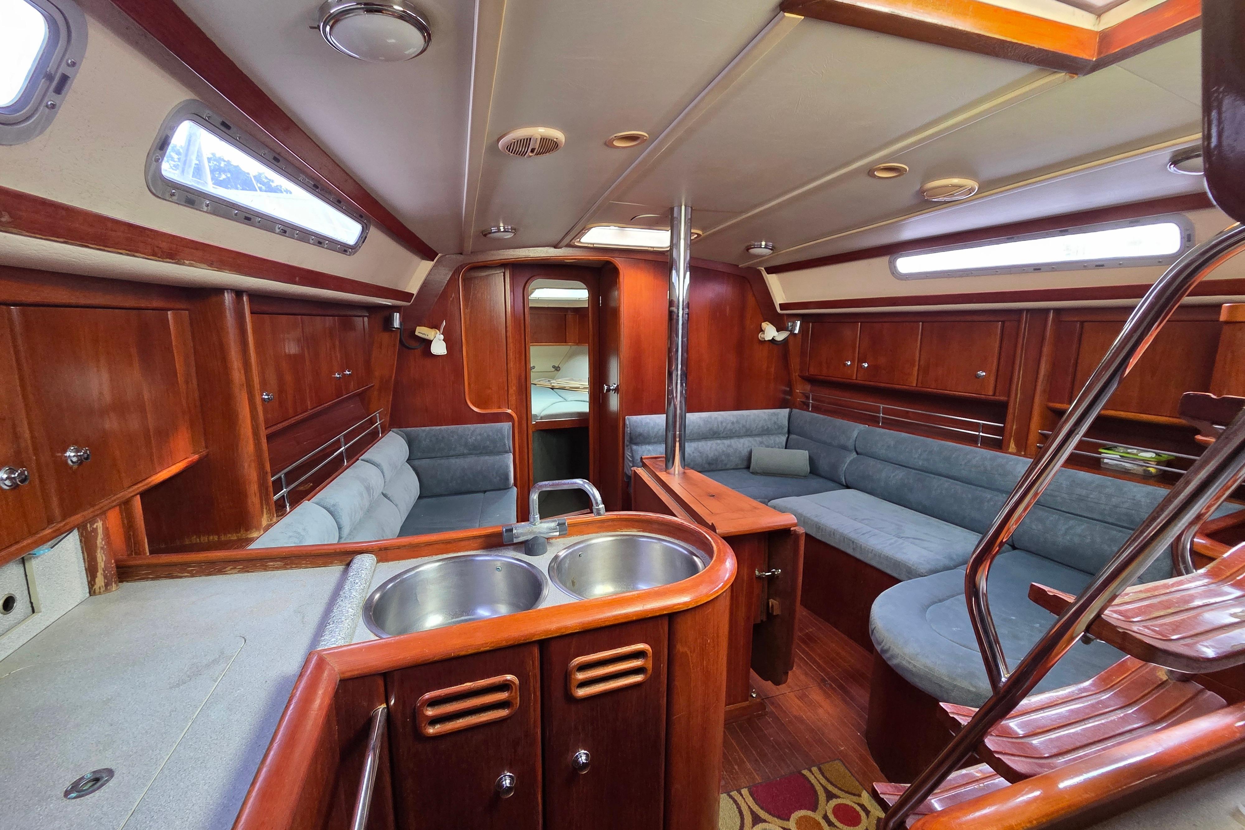 Interior of a 1995 Moody 38 sailboat with wood finish and cozy seating.