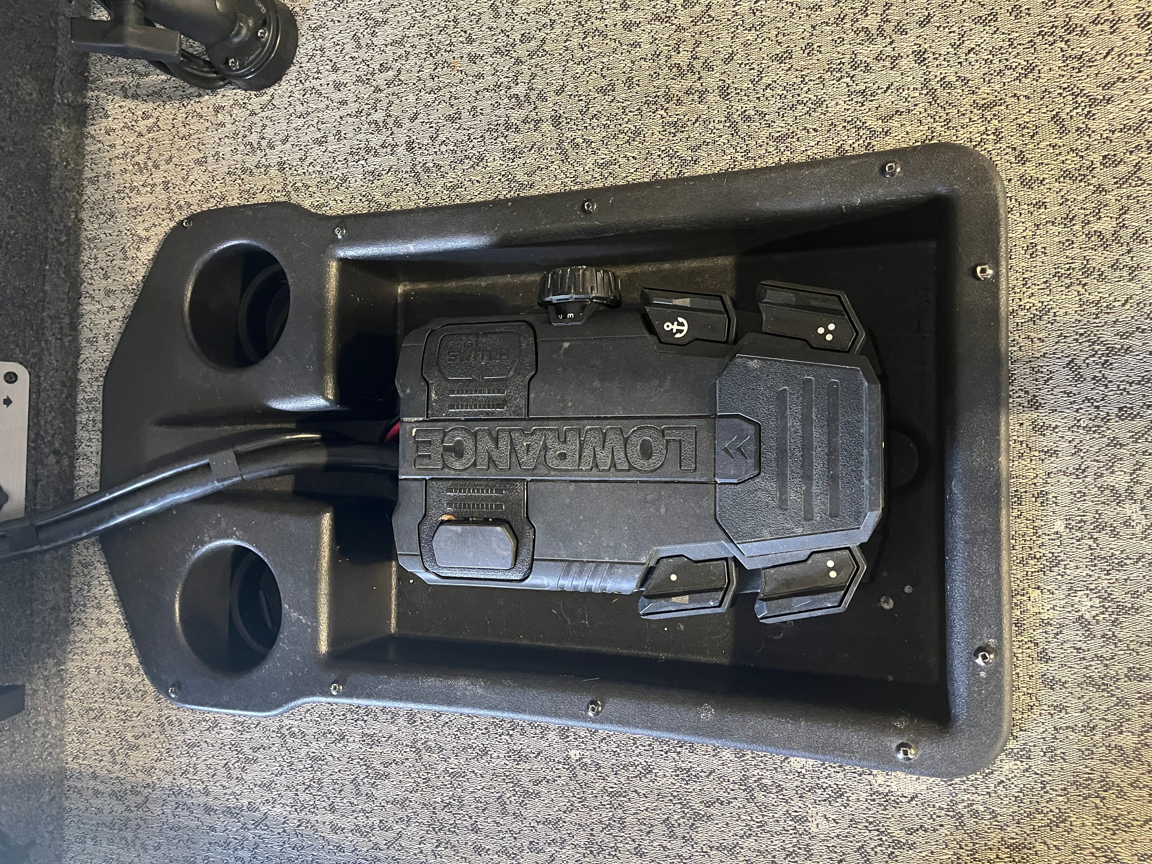 A Lowrance device is installed in a black casing on a boat, surrounded by cup holders.