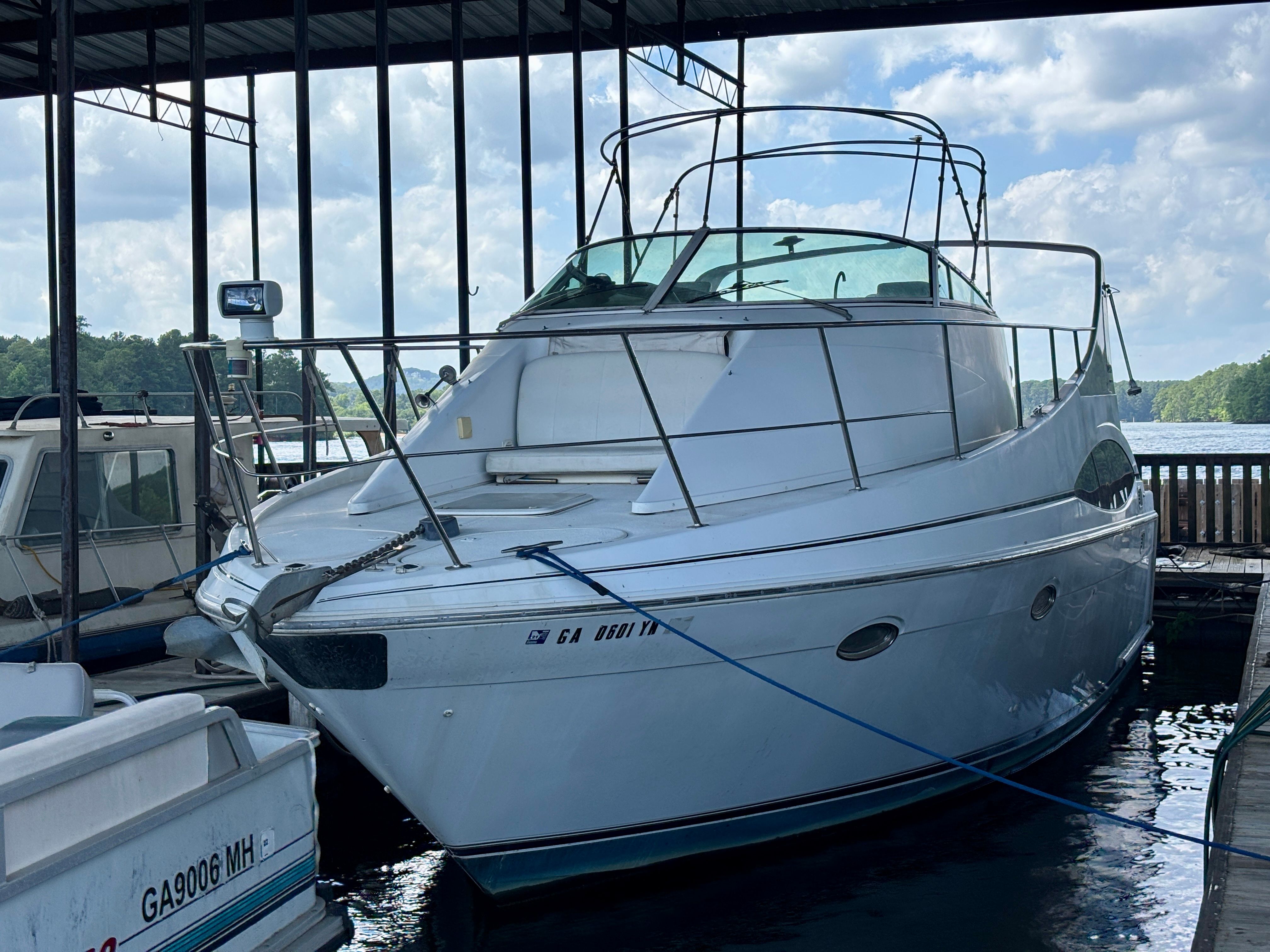 A 2001 Carver 350 Mariner is docked under a covered area. The sky is partly cloudy.