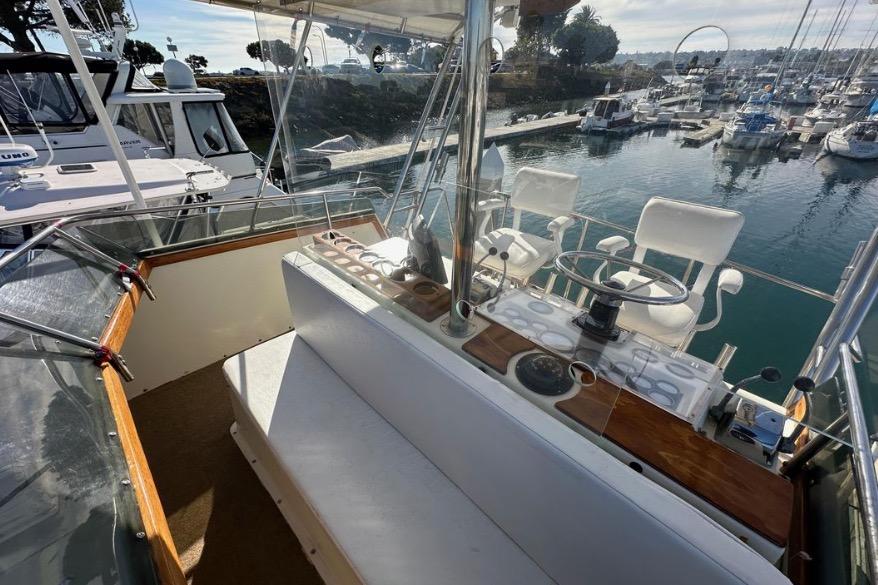 1985 Egg Harbor 33 Sedan yacht helm with marina view, featuring white seating and steering wheel.