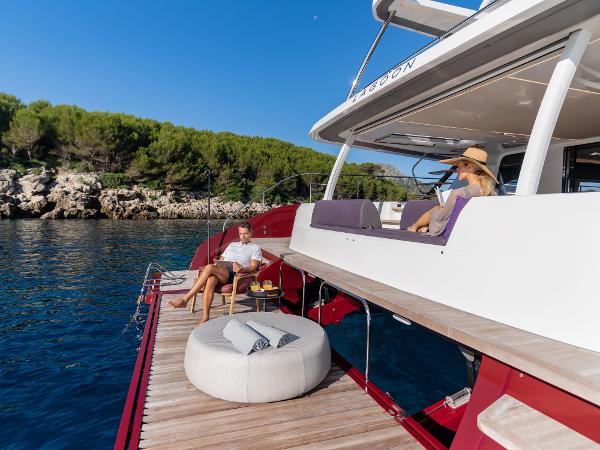 Luxury Lagoon SIXTY 7 yacht, 2025 model, with people relaxing on deck by the sea.