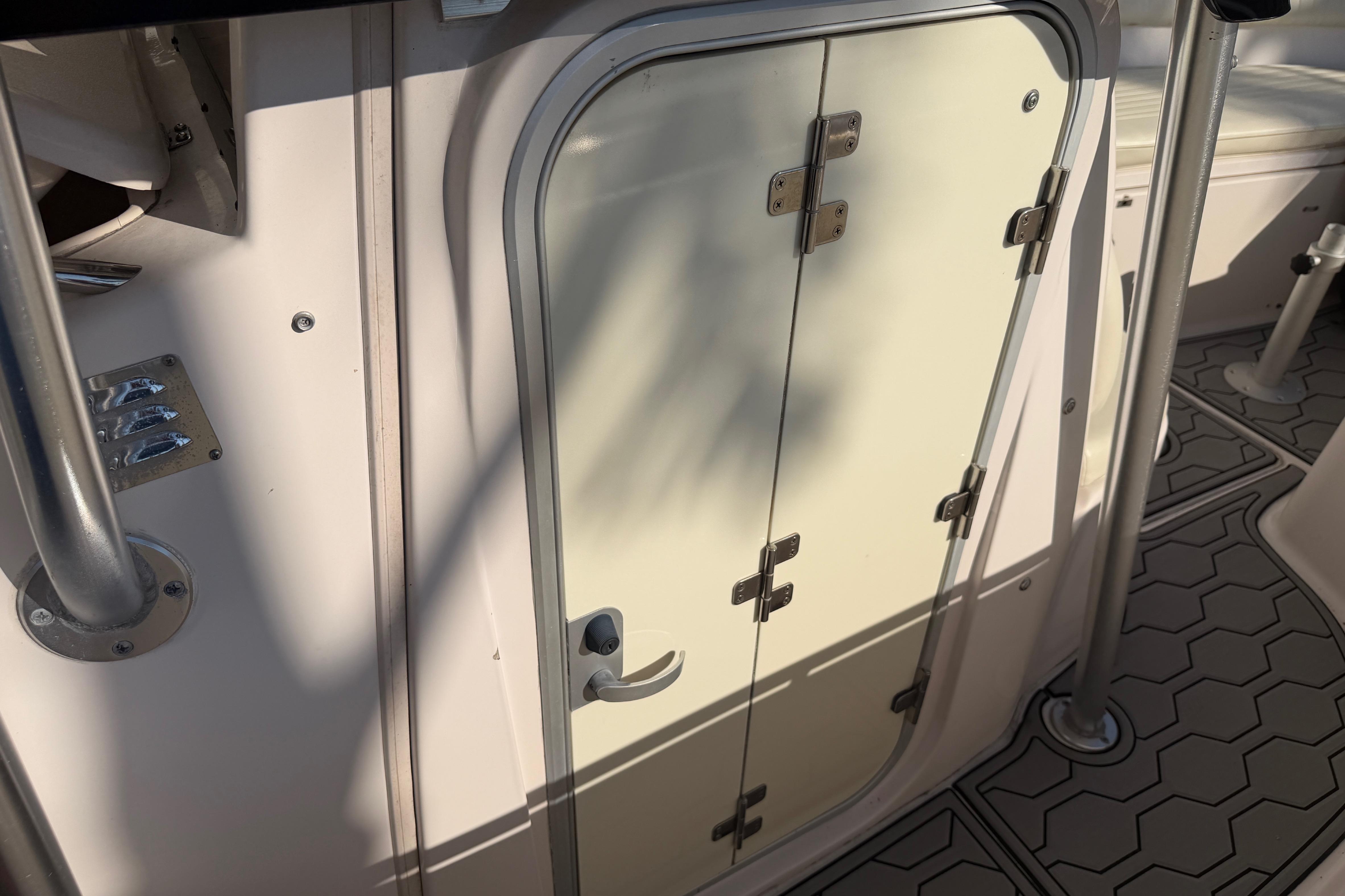 2004 Grady White 273 boat cabin door with metal hinges and textured flooring.