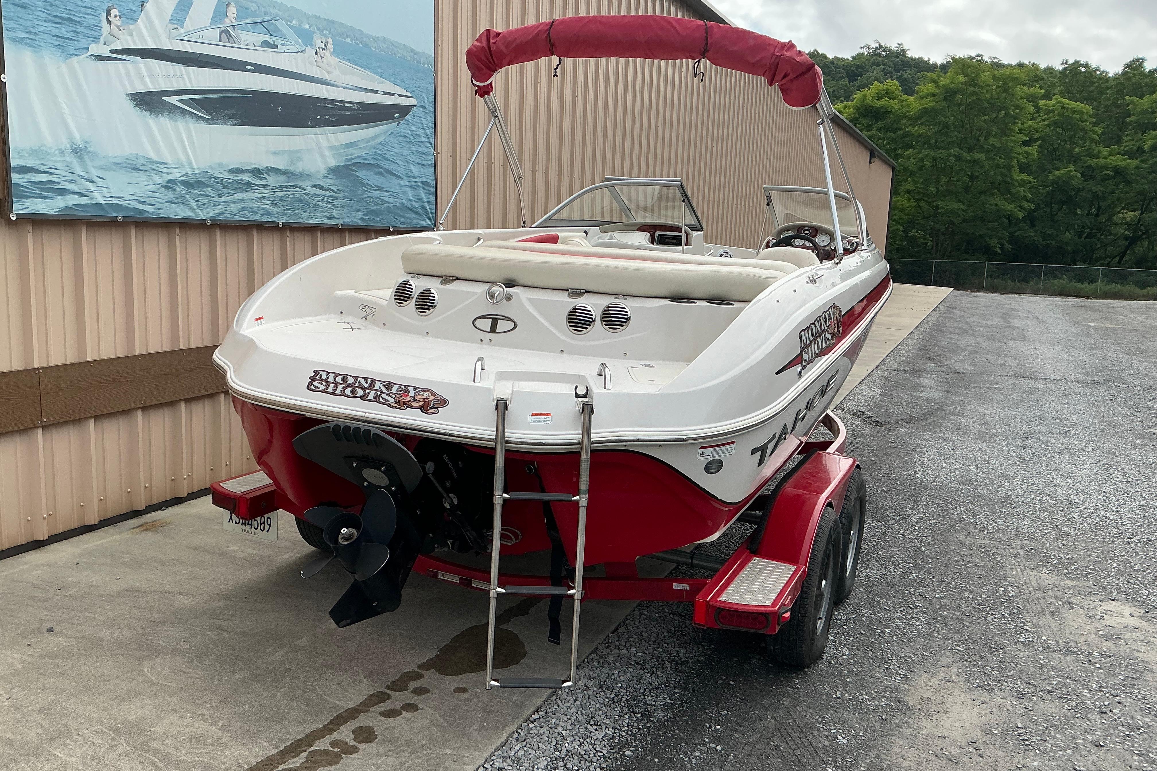 2014 Tahoe Q7i boat with red trailer, parked near a building.