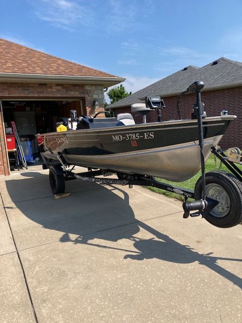 A 2000 Lund Rebel 16 boat on a trailer in front of a garage.